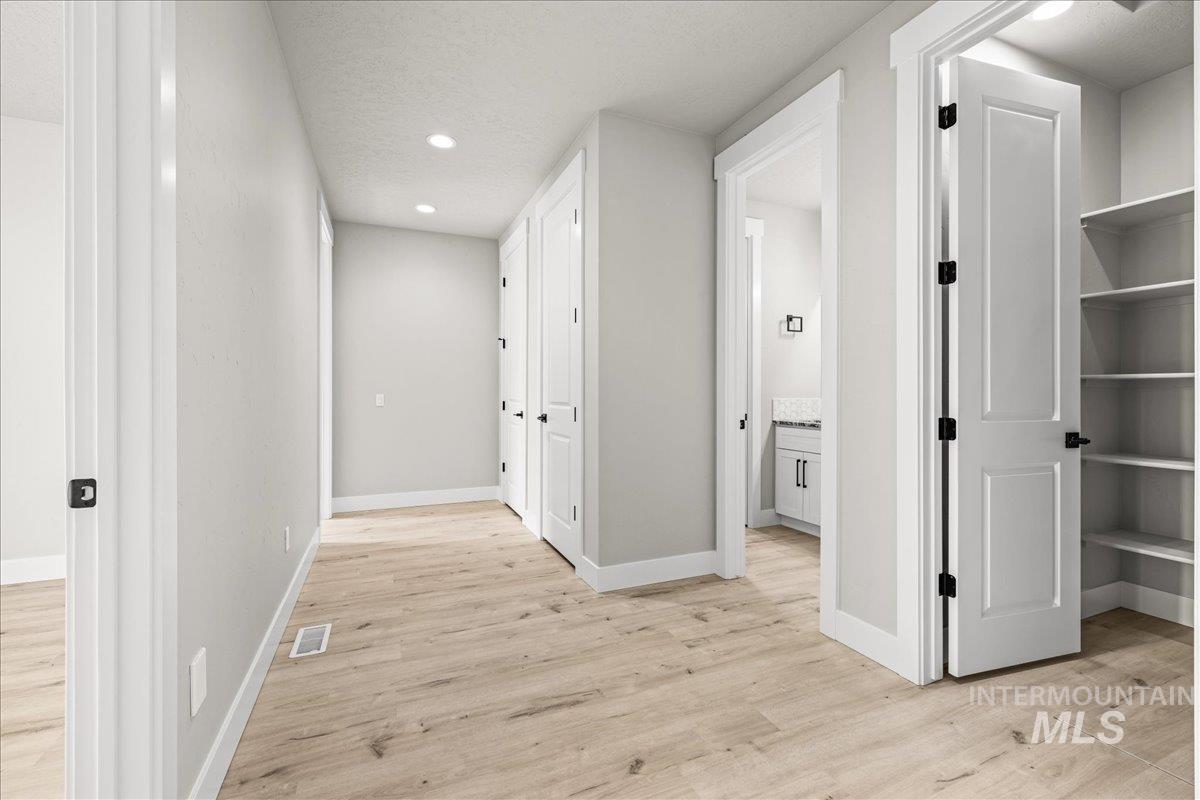 Hall with a textured ceiling, light wood-style flooring, and recessed lighting