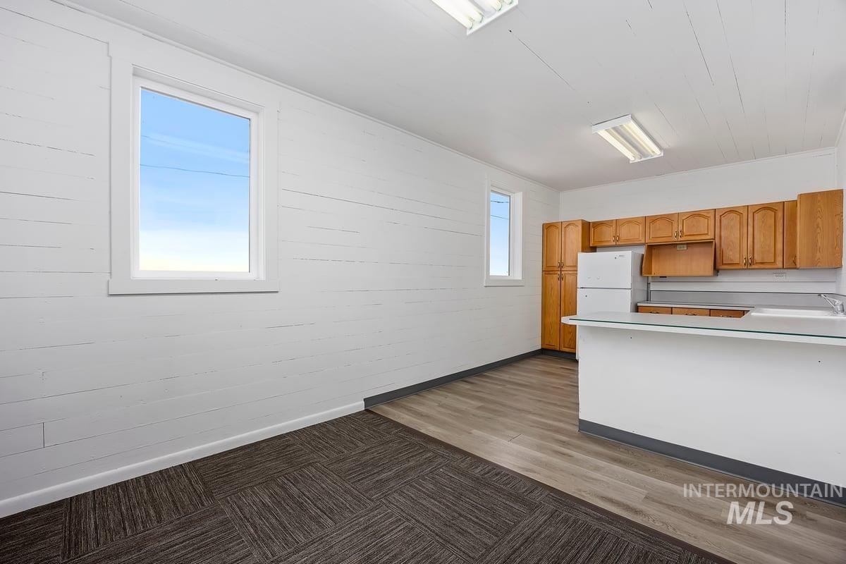 Kitchen featuring light countertops, brown cabinets, light wood-style floors, freestanding refrigerator, and a peninsula