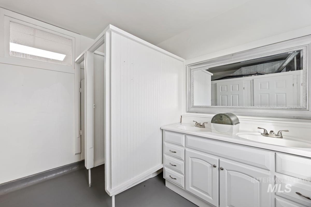 Bathroom with double vanity and concrete floors