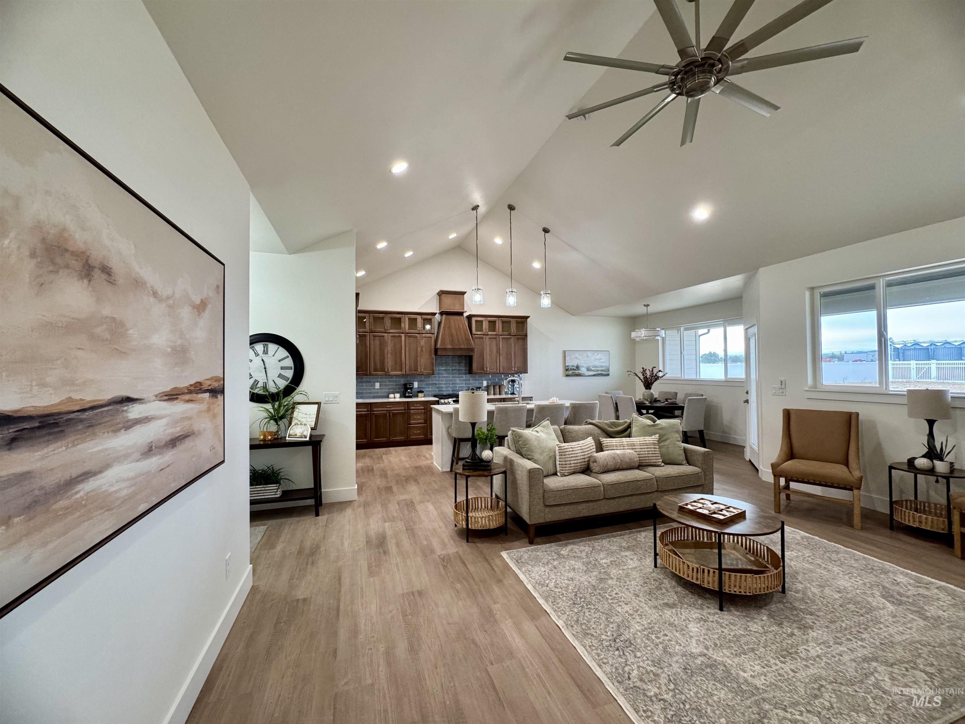 Living room with light wood-type flooring, high vaulted ceiling, ceiling fan, and recessed lighting