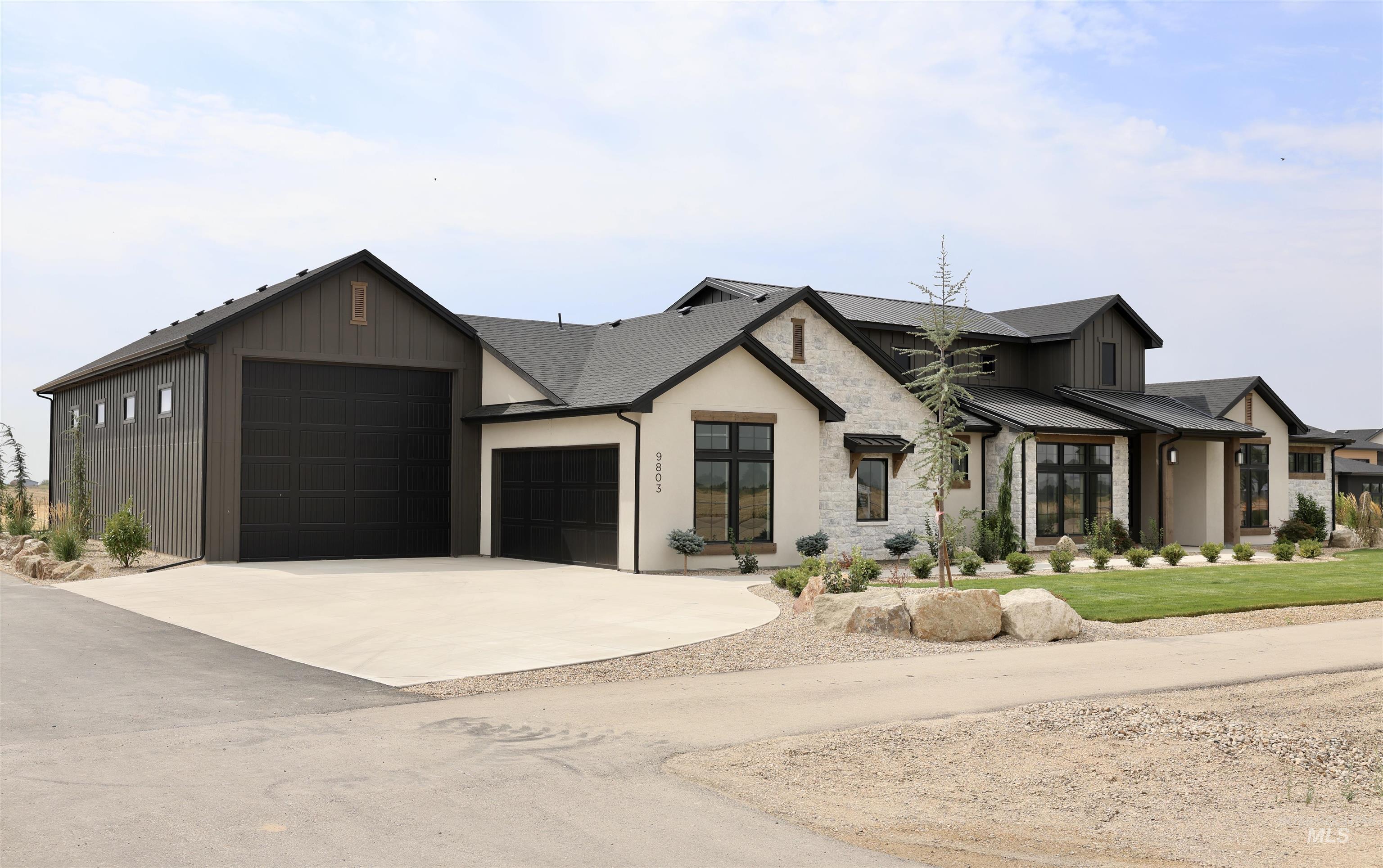 Modern inspired farmhouse featuring stone siding, an attached garage, and driveway