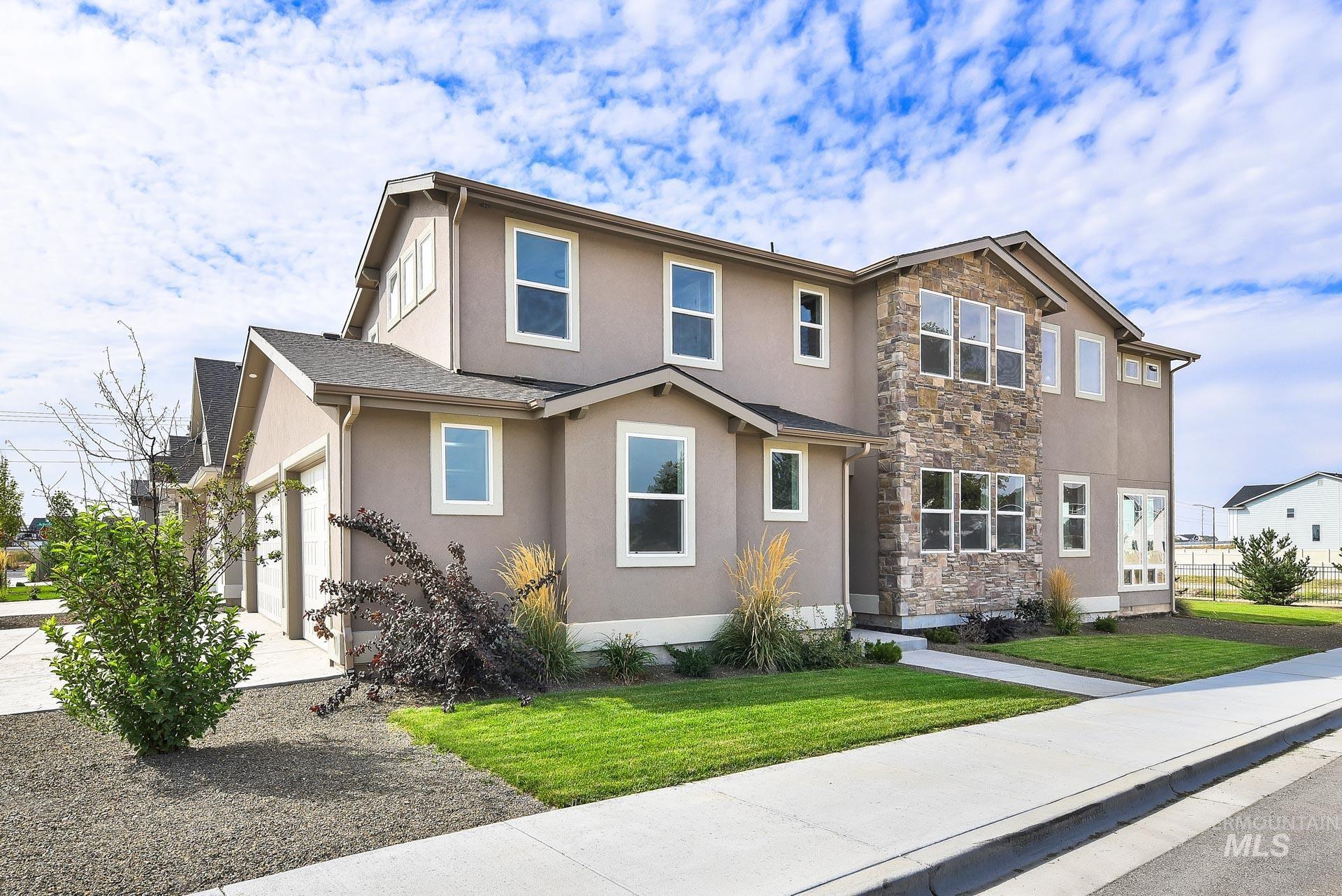 View of front of home with a garage, stone siding, stucco siding, a front yard, and concrete driveway