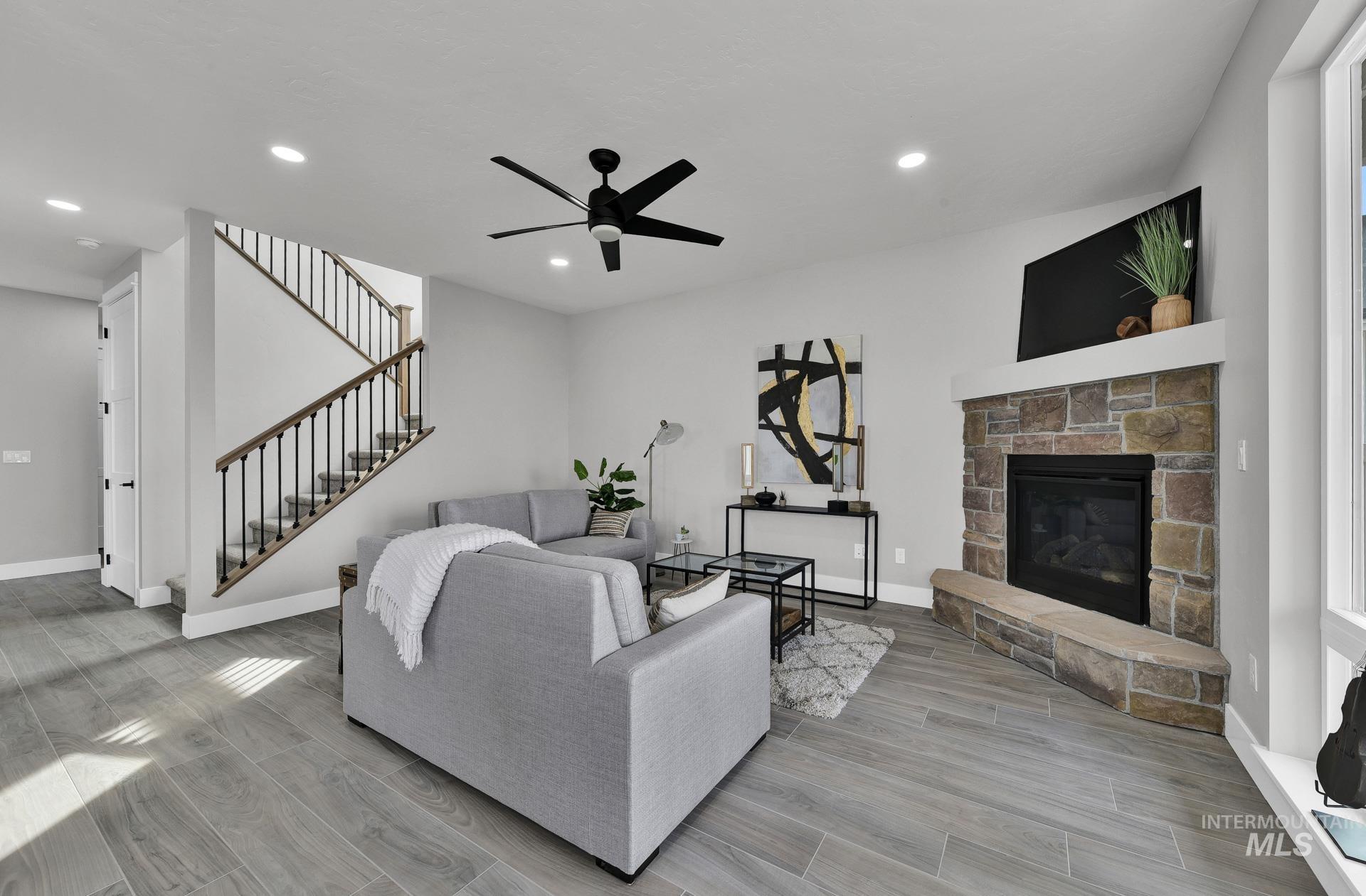 Living area featuring wood finish floors, stairway, a fireplace, recessed lighting, and a ceiling fan