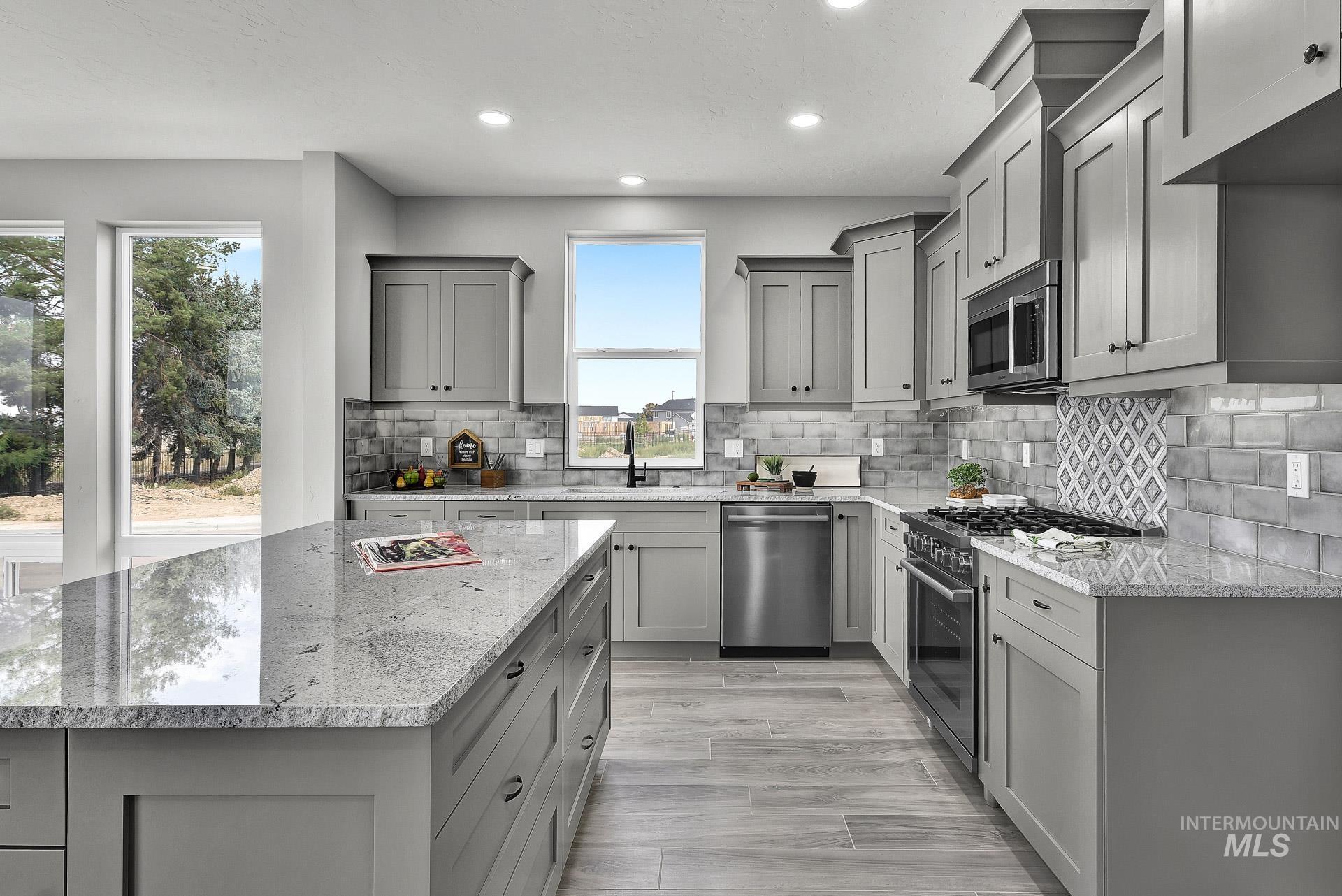 Kitchen featuring gray cabinets, stainless steel appliances, light stone countertops, recessed lighting, and tasteful backsplash