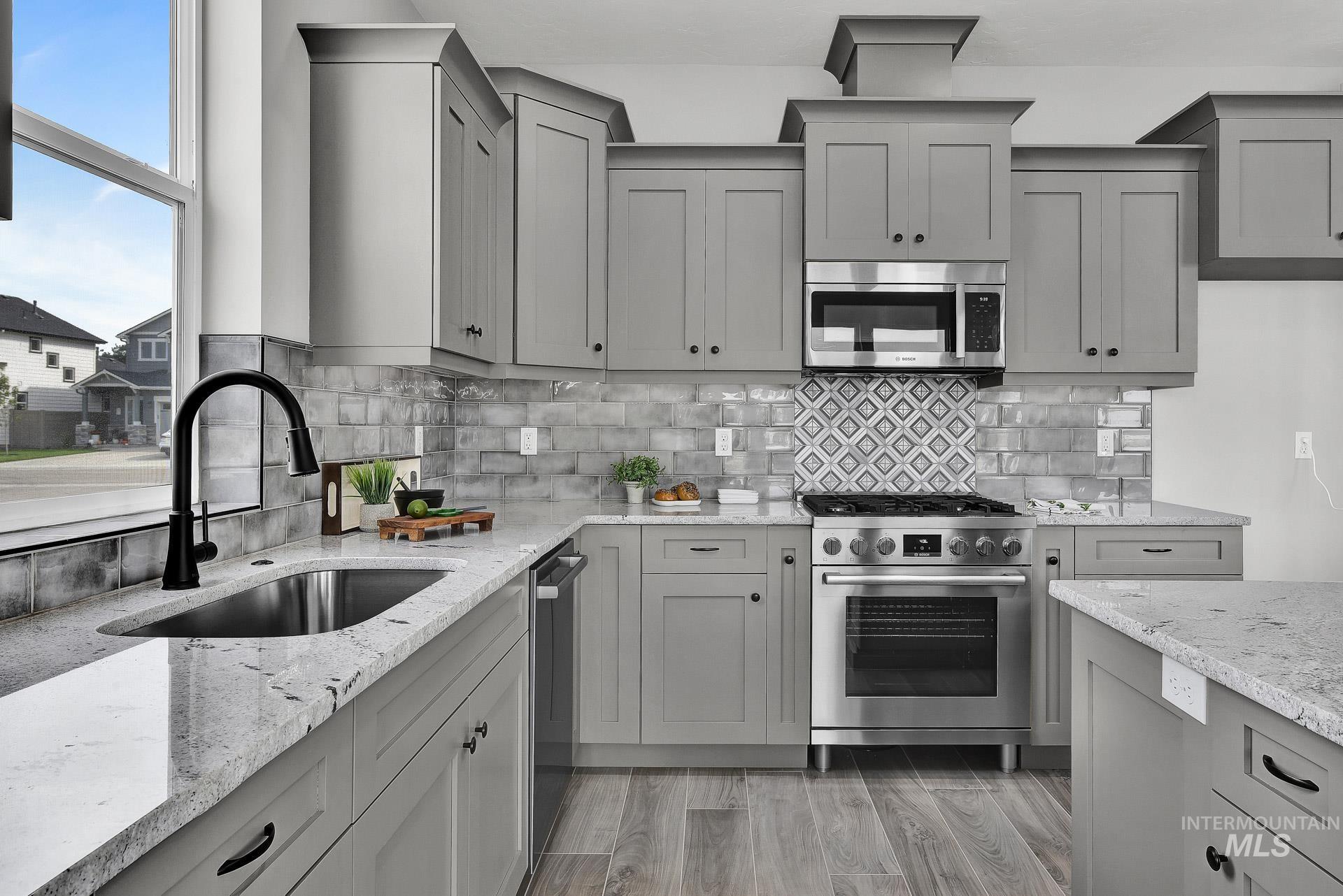 Kitchen featuring gray cabinets, stainless steel appliances, and light stone counters