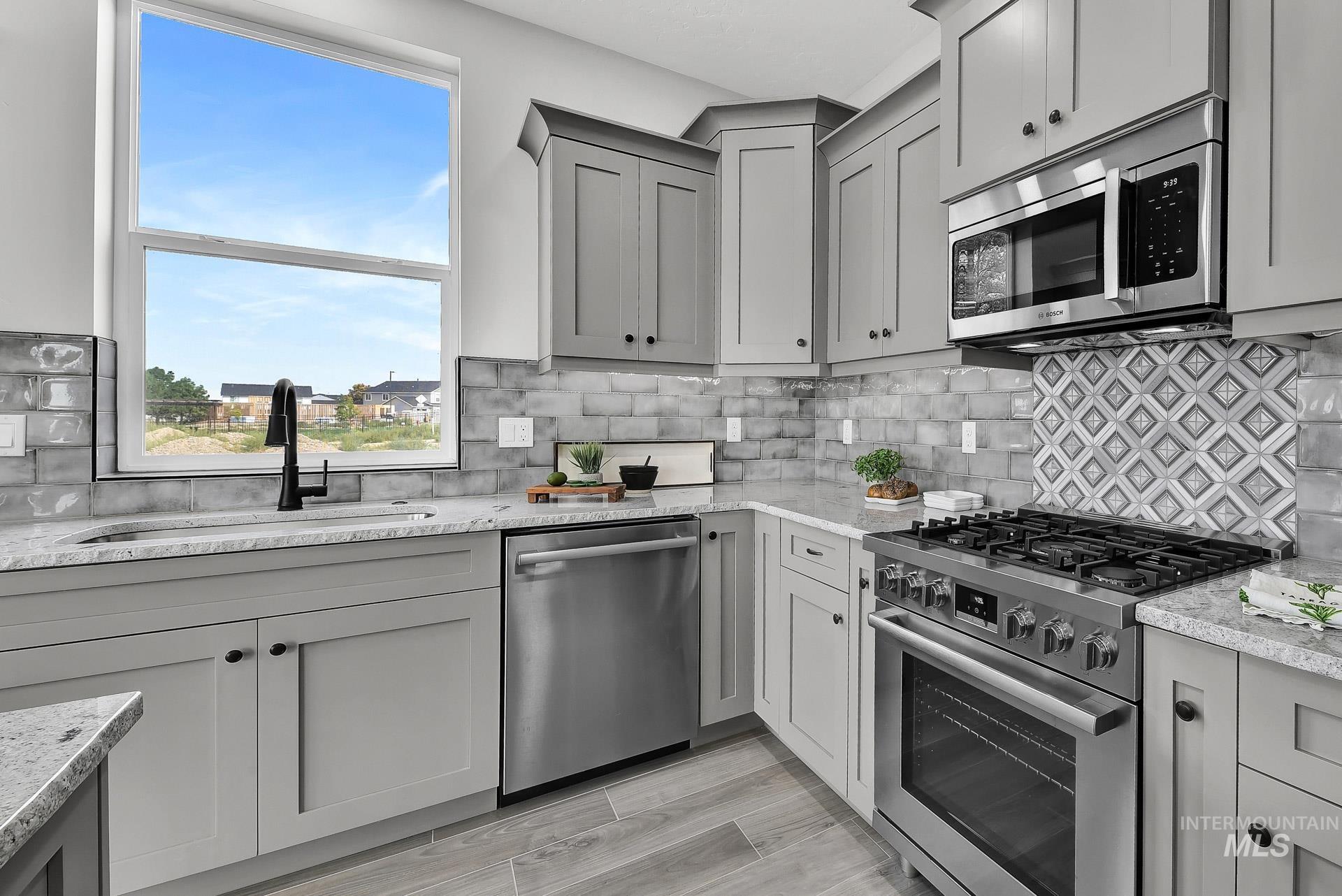 Kitchen with gray cabinetry, stainless steel appliances, and decorative backsplash