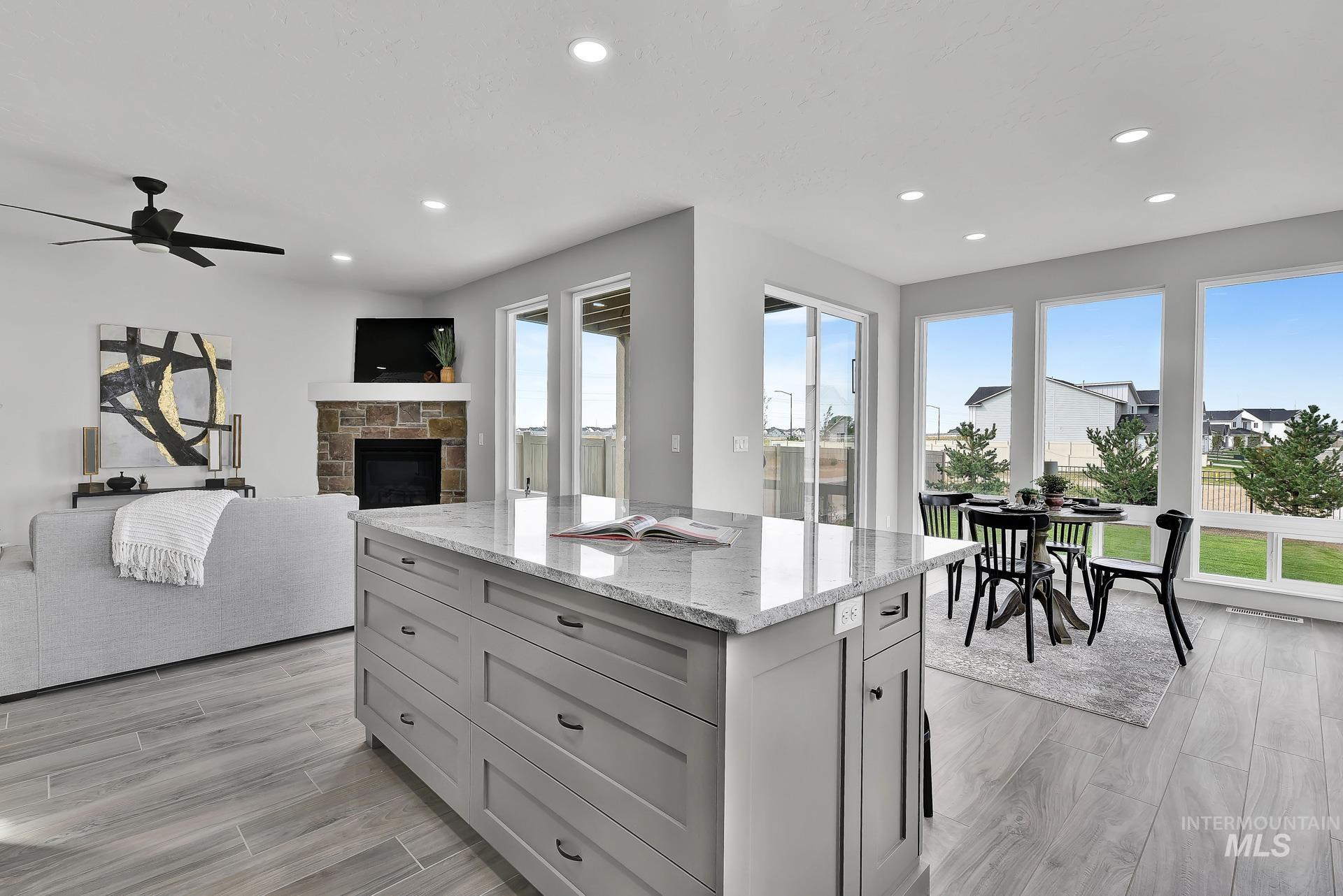 Kitchen with light stone countertops, a center island, a stone fireplace, open floor plan, and recessed lighting