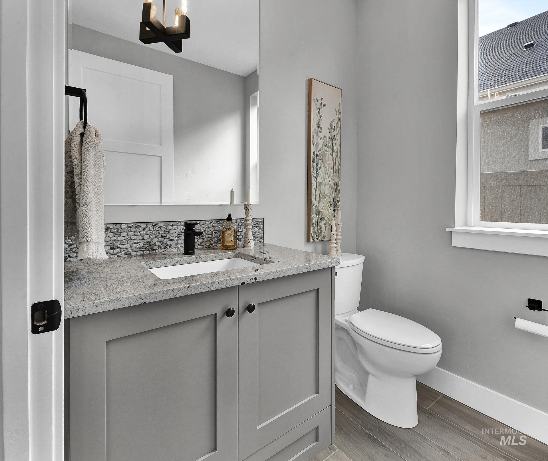 Bathroom featuring vanity, light wood-type flooring, backsplash, and plenty of natural light