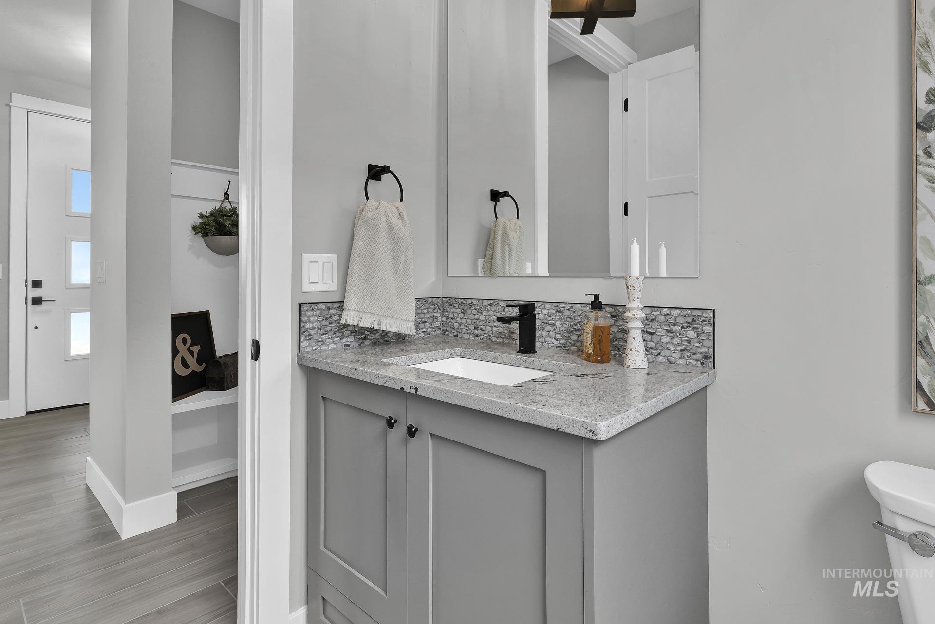 Bathroom featuring decorative backsplash, vanity, and light wood finished floors