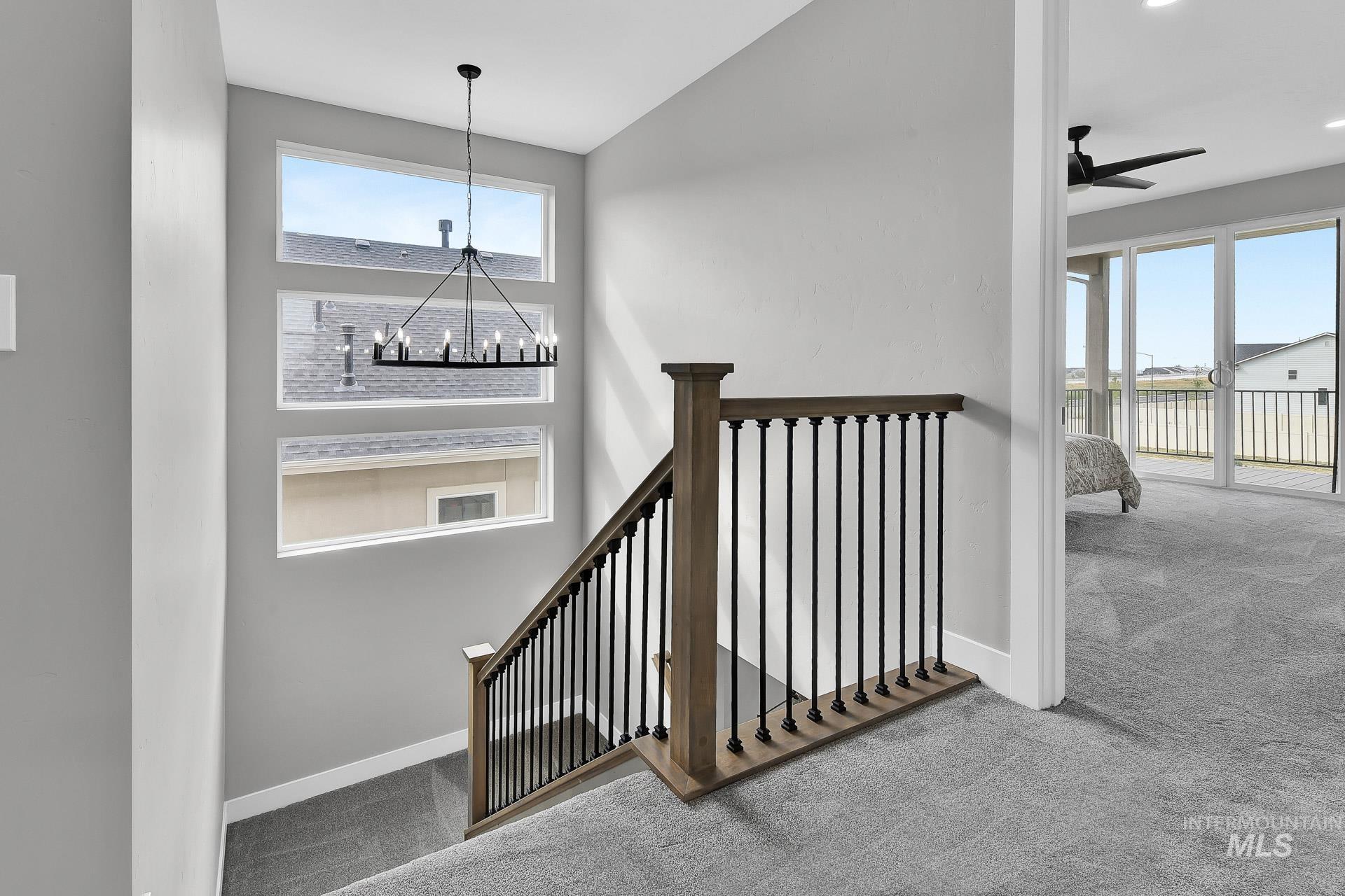 Stairs with carpet flooring, ceiling fan, a chandelier, and a high ceiling