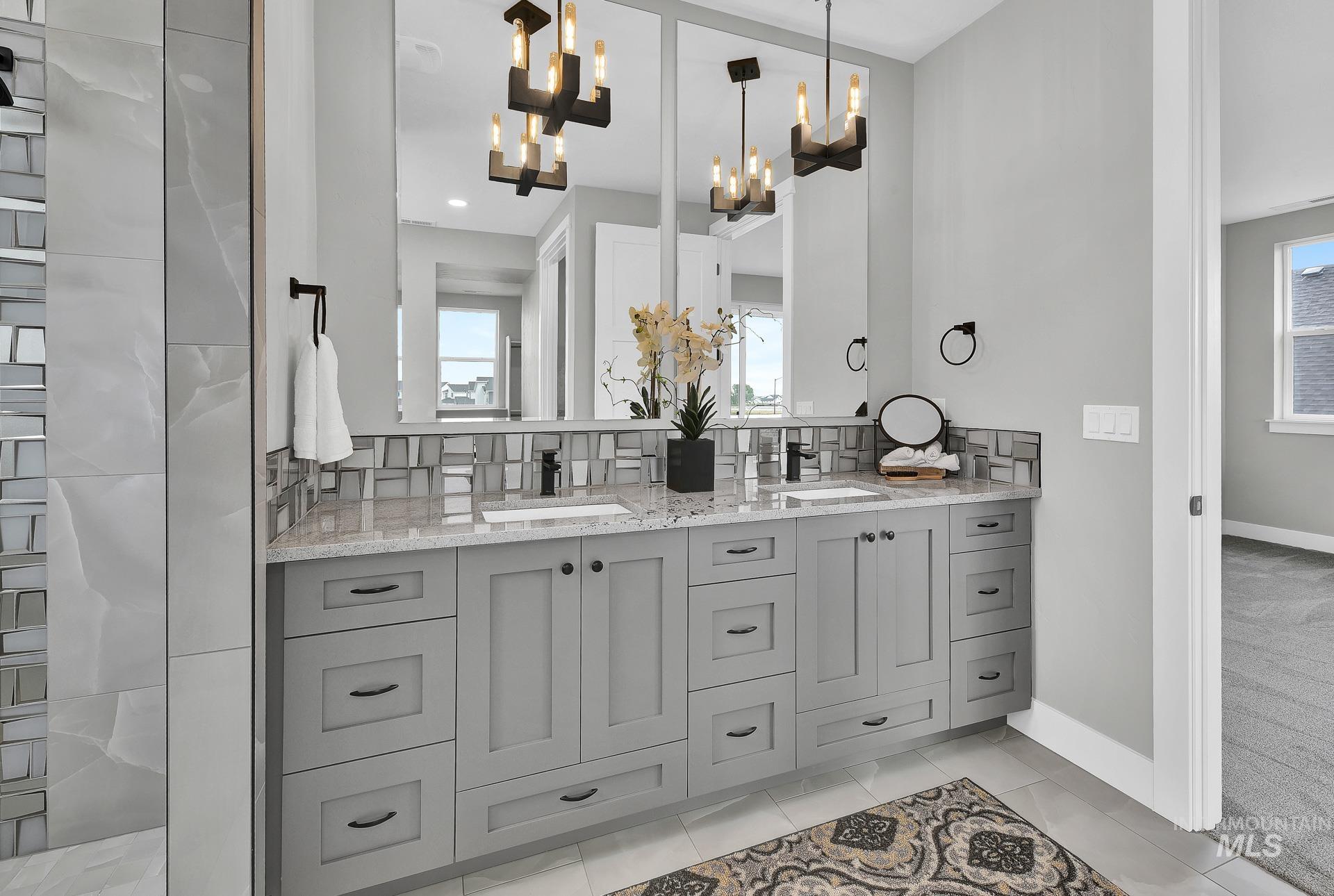 Bathroom featuring double vanity, tasteful backsplash, and light tile patterned floors