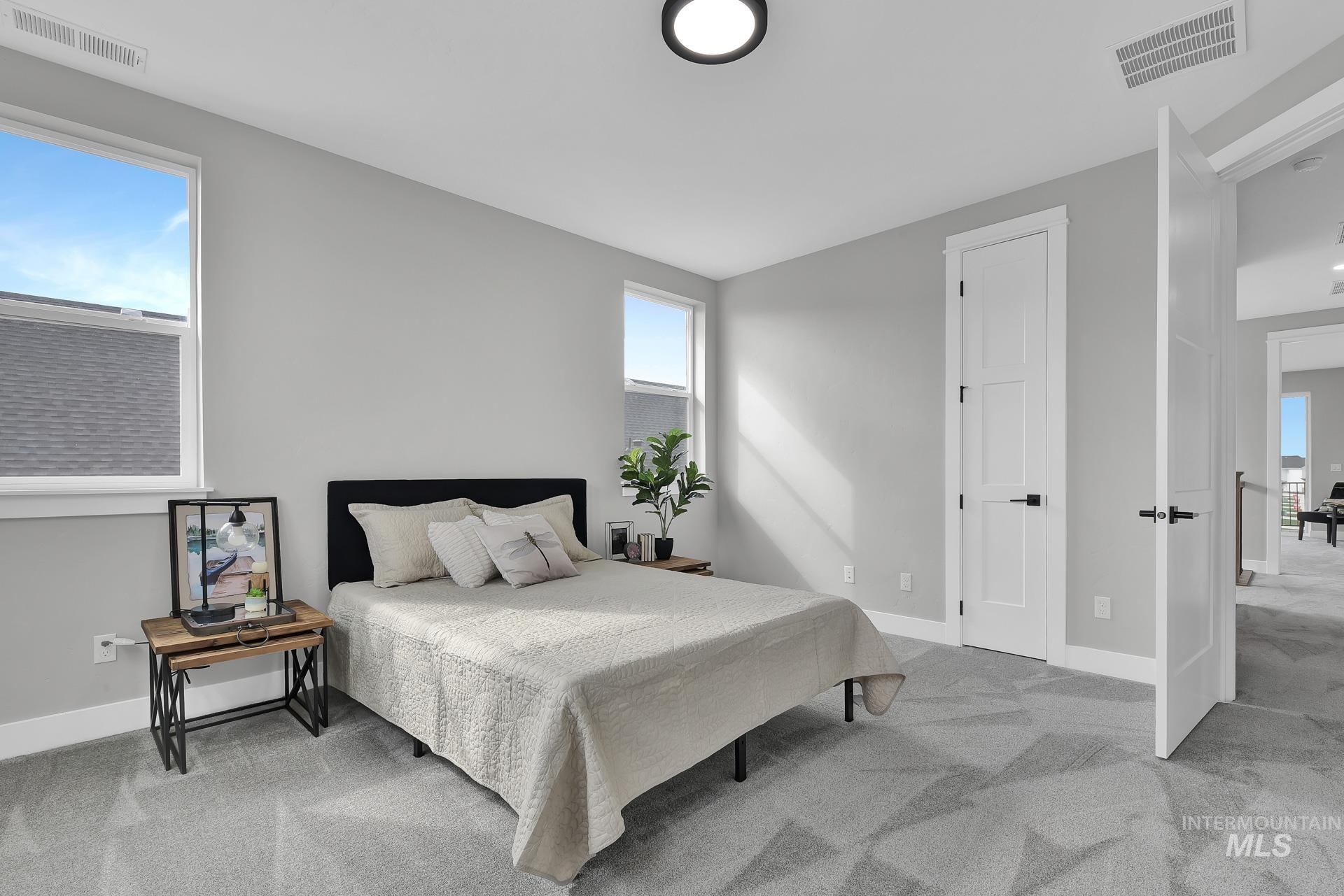 Bedroom featuring light colored carpet and multiple windows