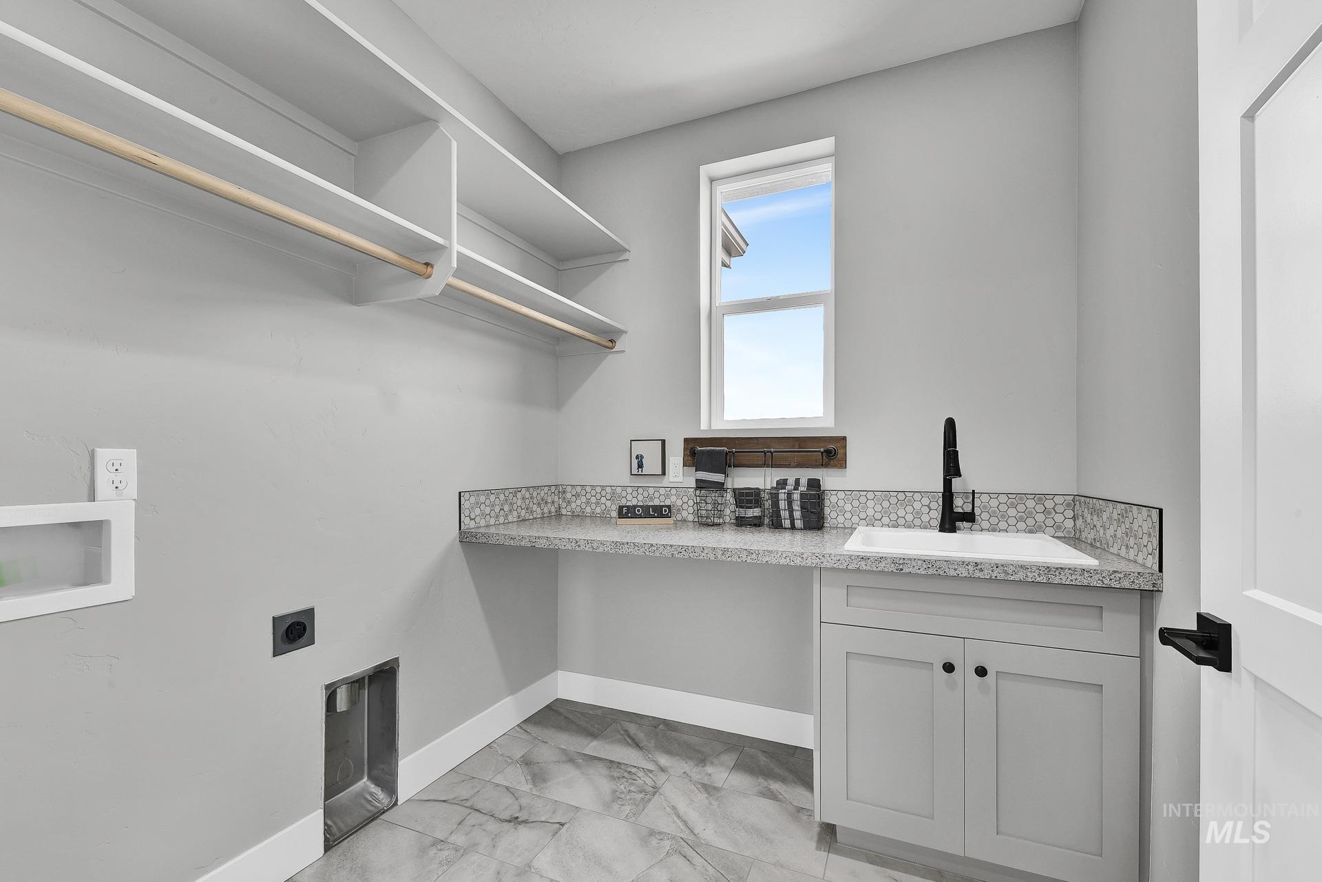 Laundry room featuring light marble finish floors, washer hookup, electric dryer hookup, and cabinet space