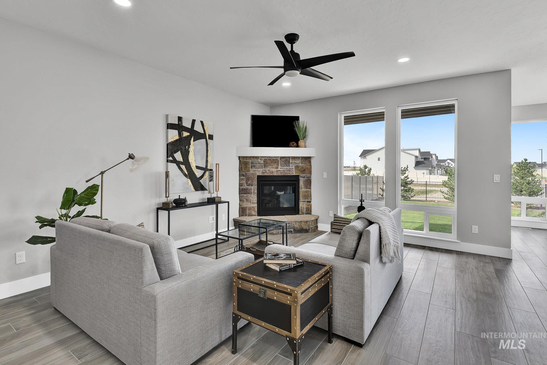 Living room featuring wood finished floors, a stone fireplace, ceiling fan, and recessed lighting