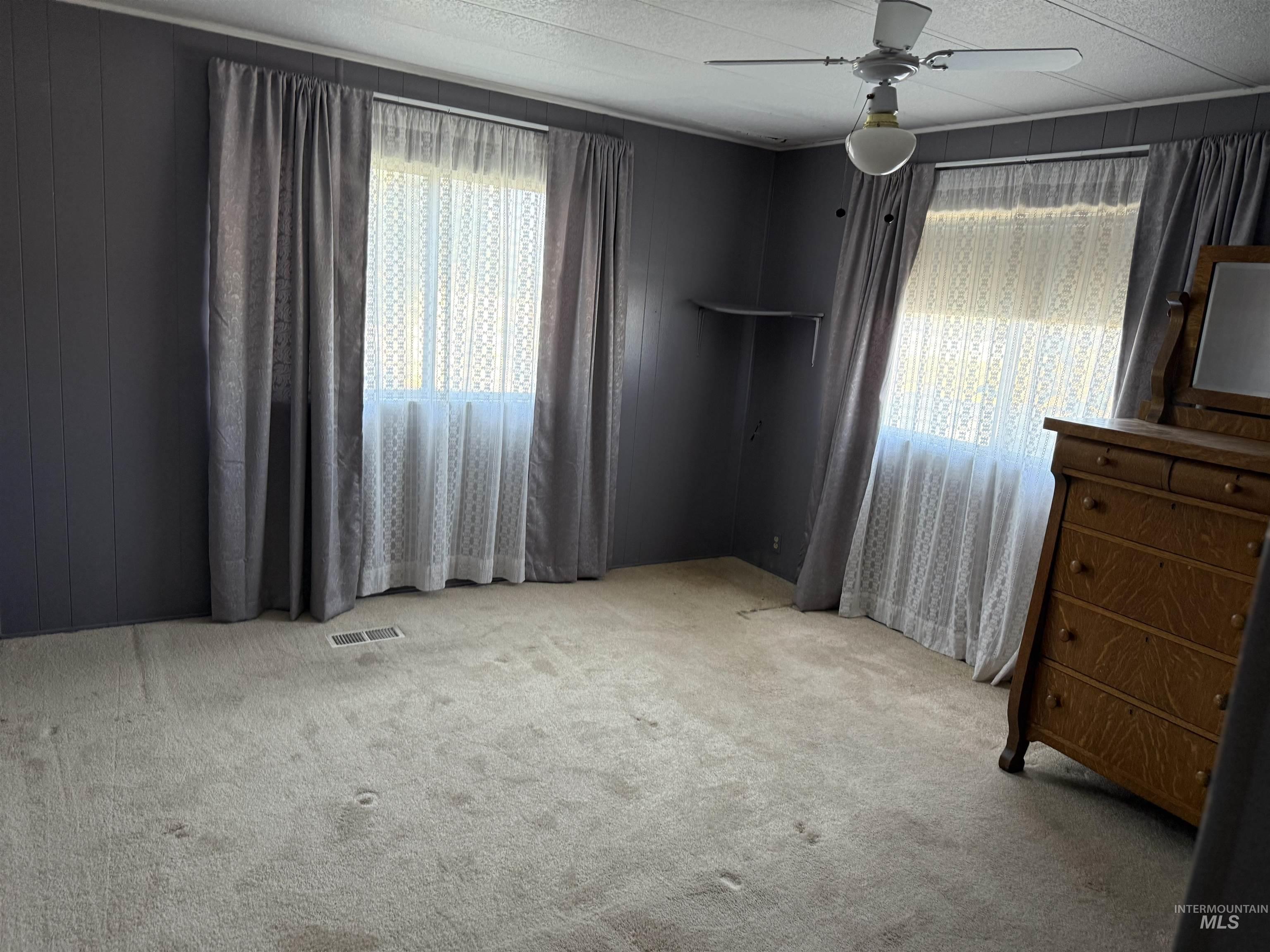 Unfurnished bedroom featuring wooden walls, carpet flooring, and ceiling fan
