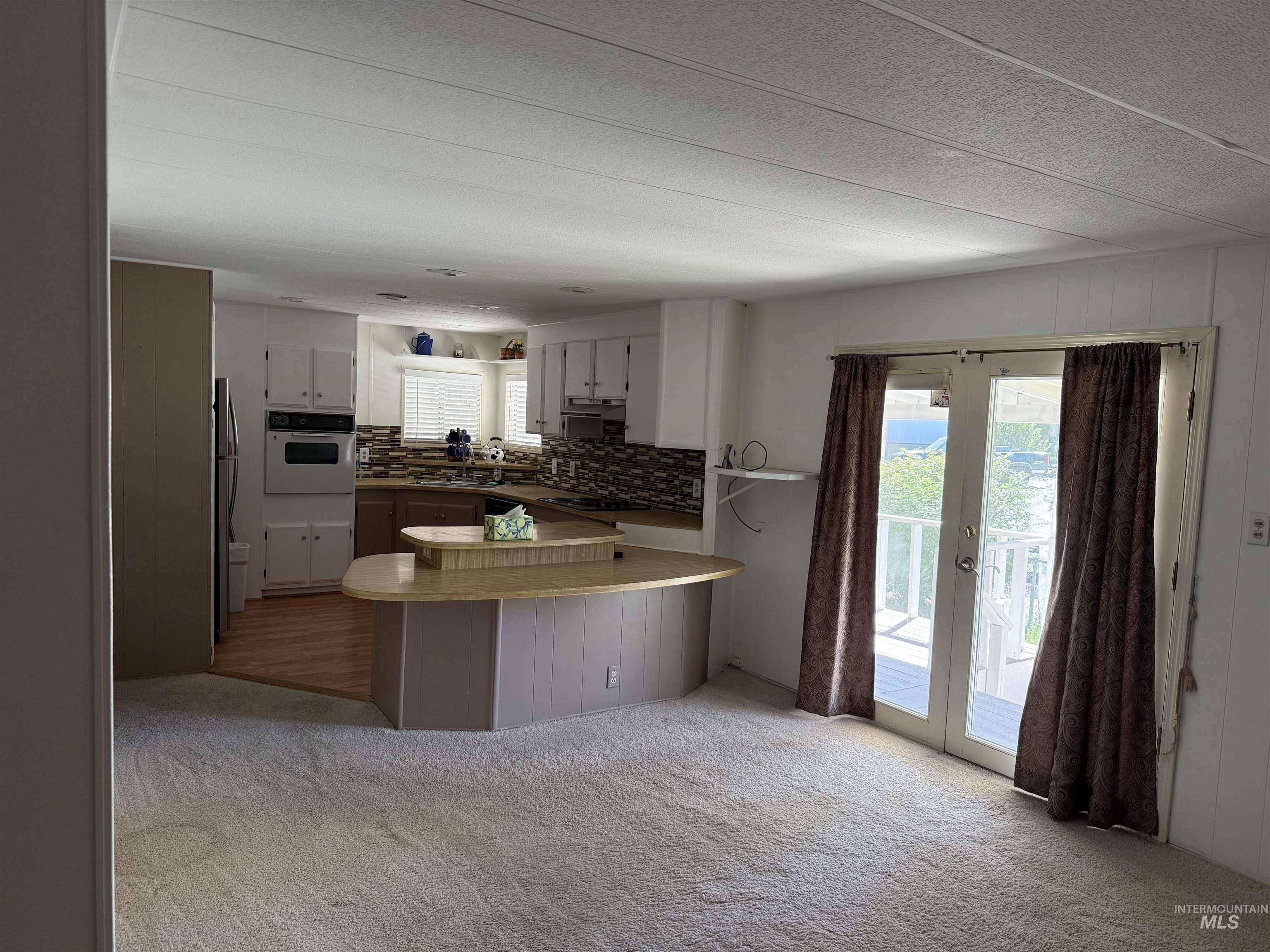 Kitchen with backsplash, a peninsula, oven, light carpet, and french doors