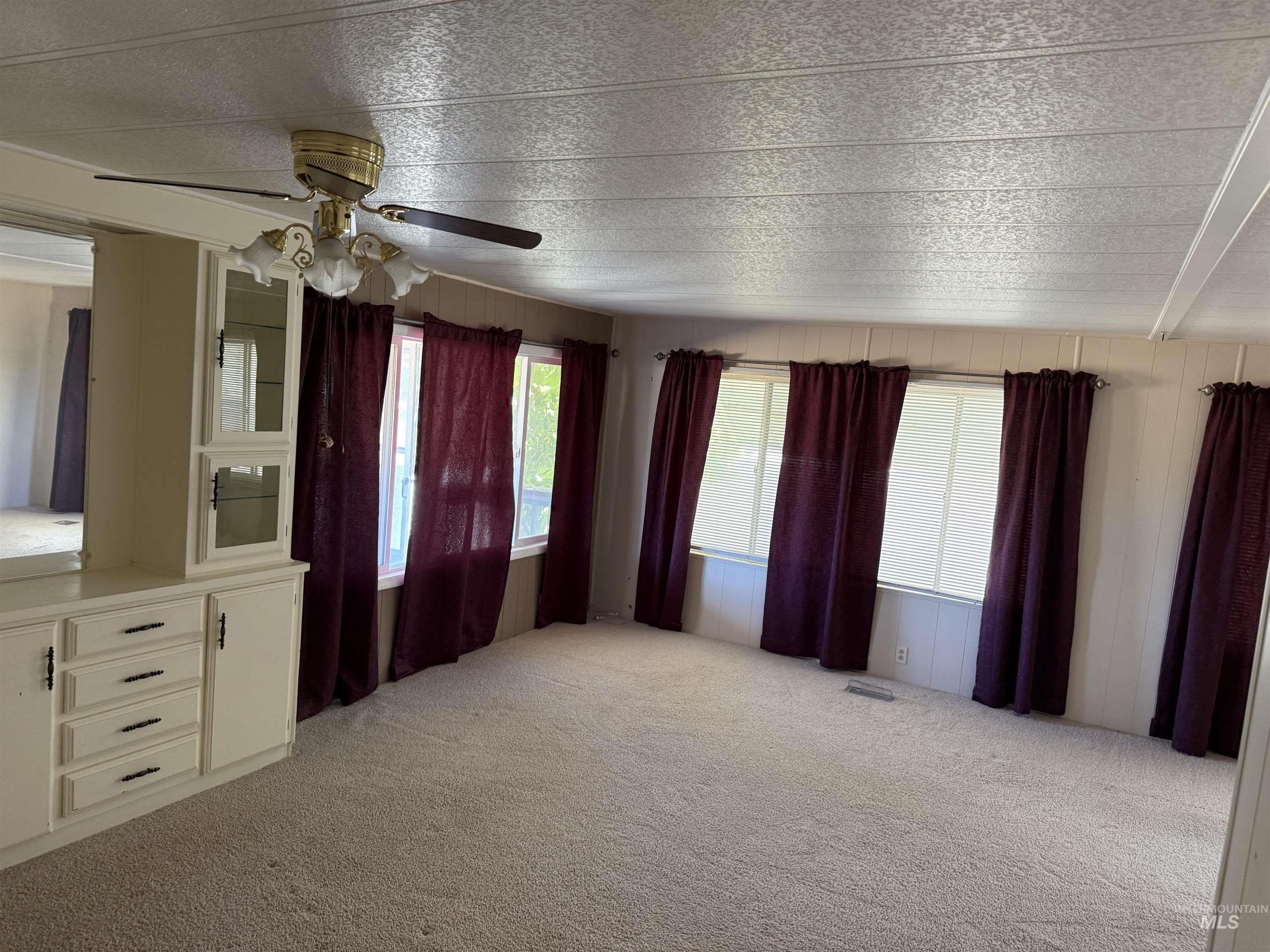 Unfurnished living room featuring light carpet and a ceiling fan