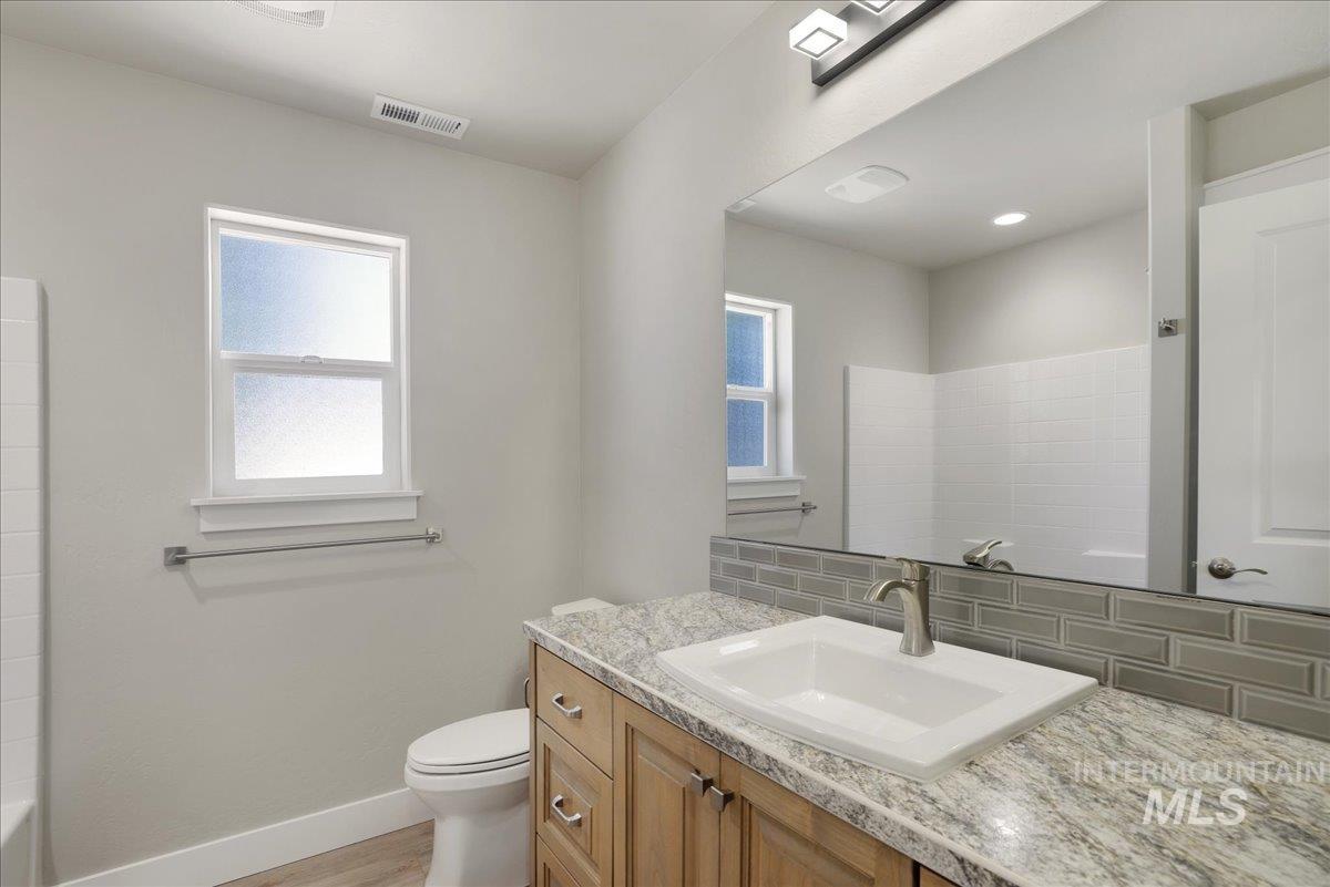 Bathroom with decorative backsplash, vanity, and wood finished floors
