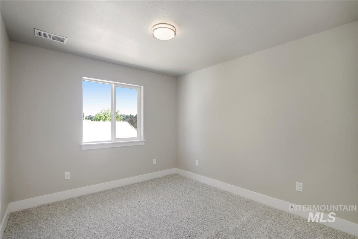 Carpeted spare room featuring baseboards
