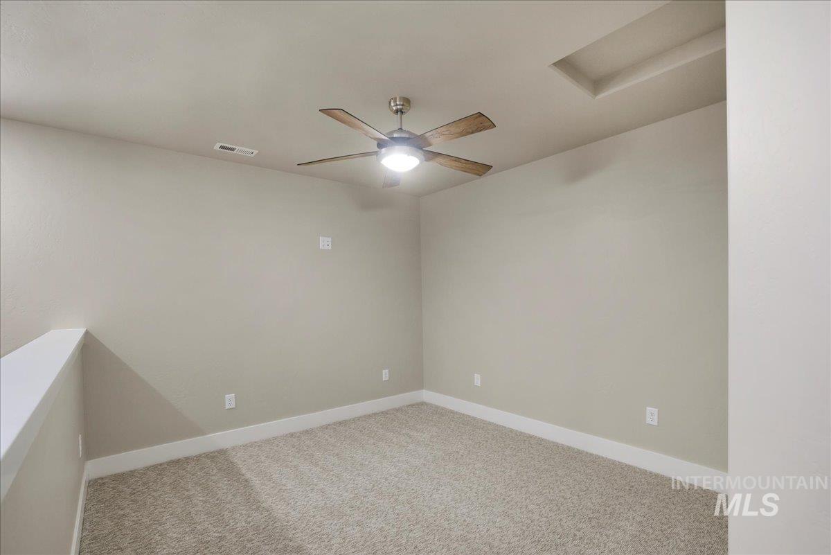 Carpeted spare room with attic access and ceiling fan