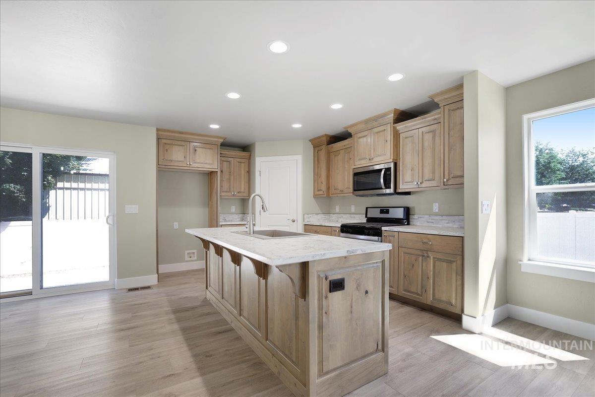 Kitchen featuring stainless steel appliances, plenty of natural light, light wood-style floors, and recessed lighting