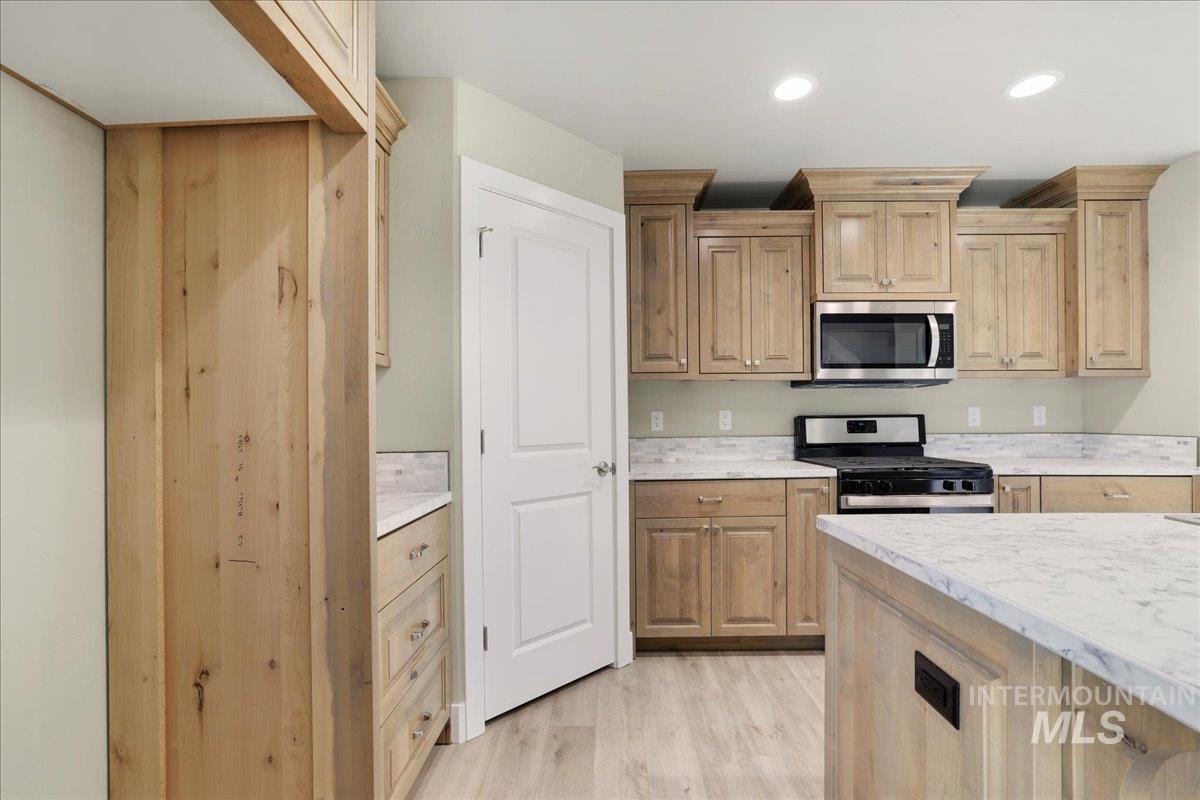 Kitchen featuring stainless steel appliances, light countertops, light wood-type flooring, light brown cabinets, and recessed lighting
