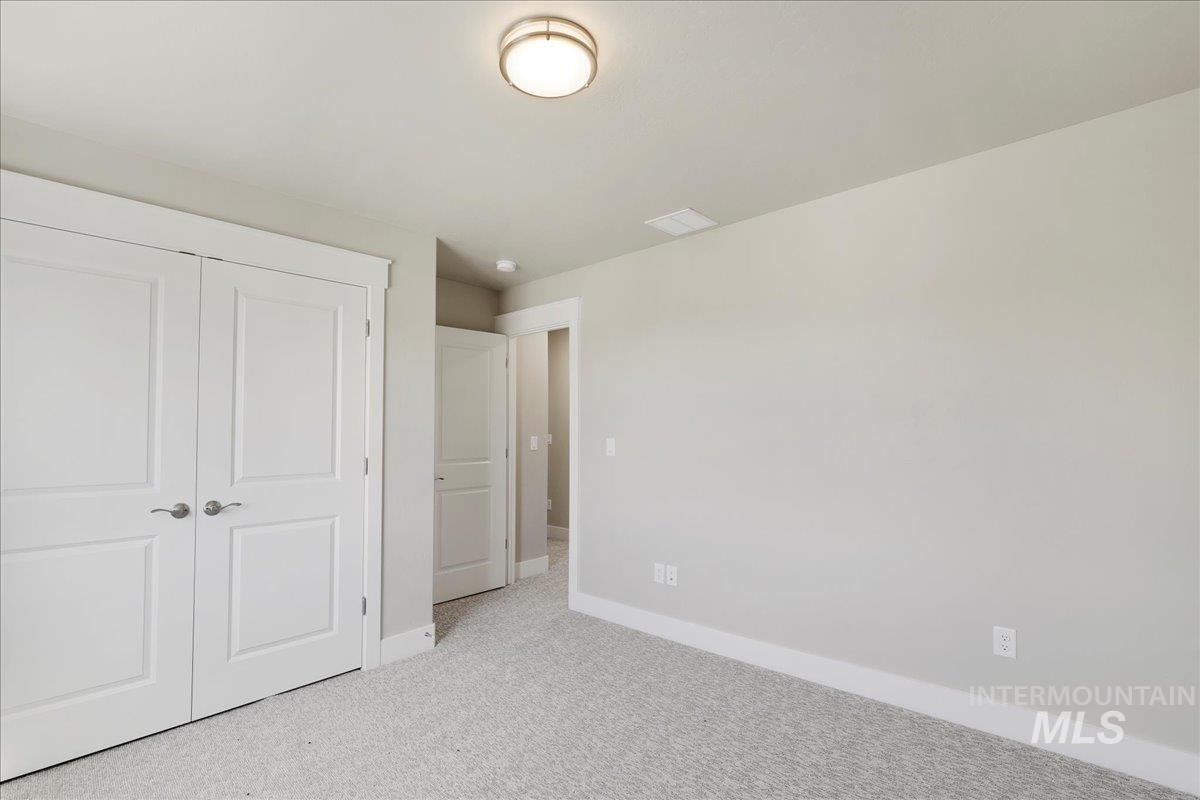 Unfurnished bedroom featuring light carpet and a closet