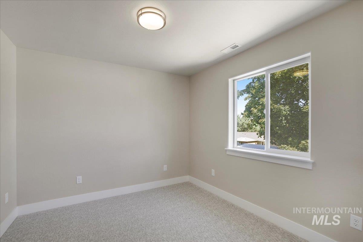 Spare room featuring light colored carpet and baseboards