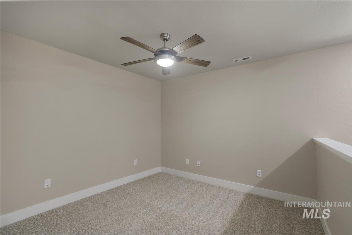Empty room featuring ceiling fan and light carpet