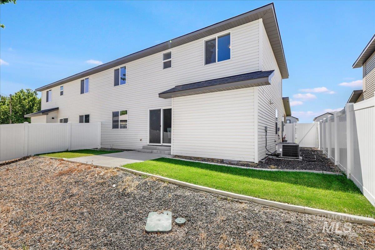 Back of property with entry steps, a fenced backyard, and a patio area