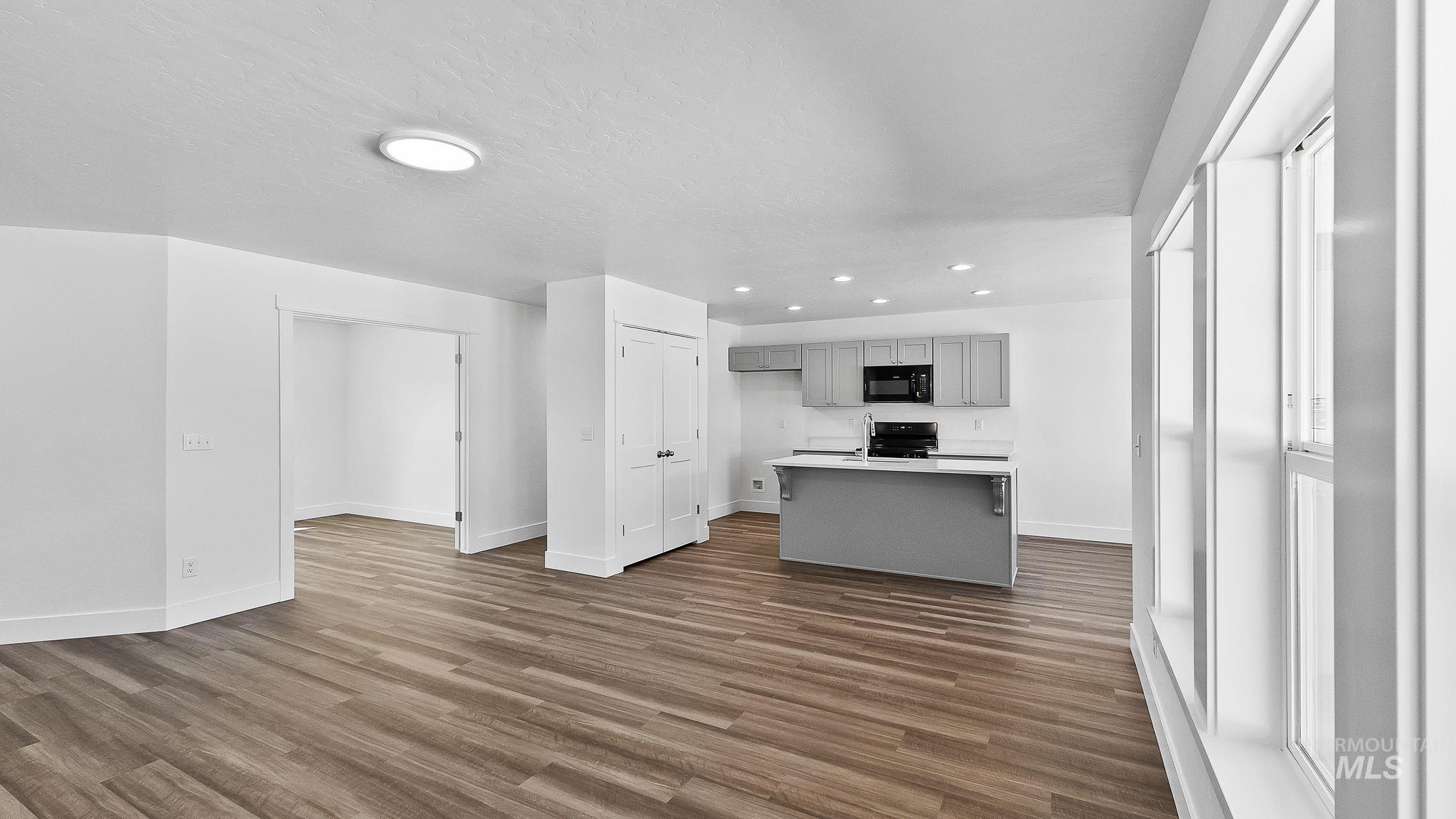 Kitchen with gray cabinetry, light countertops, dark wood finished floors, recessed lighting, and a kitchen island with sink