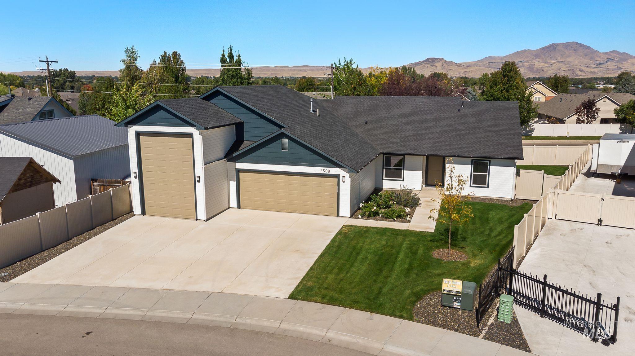 Ranch-style house featuring a garage, concrete driveway, a shingled roof, a residential view, and a gate