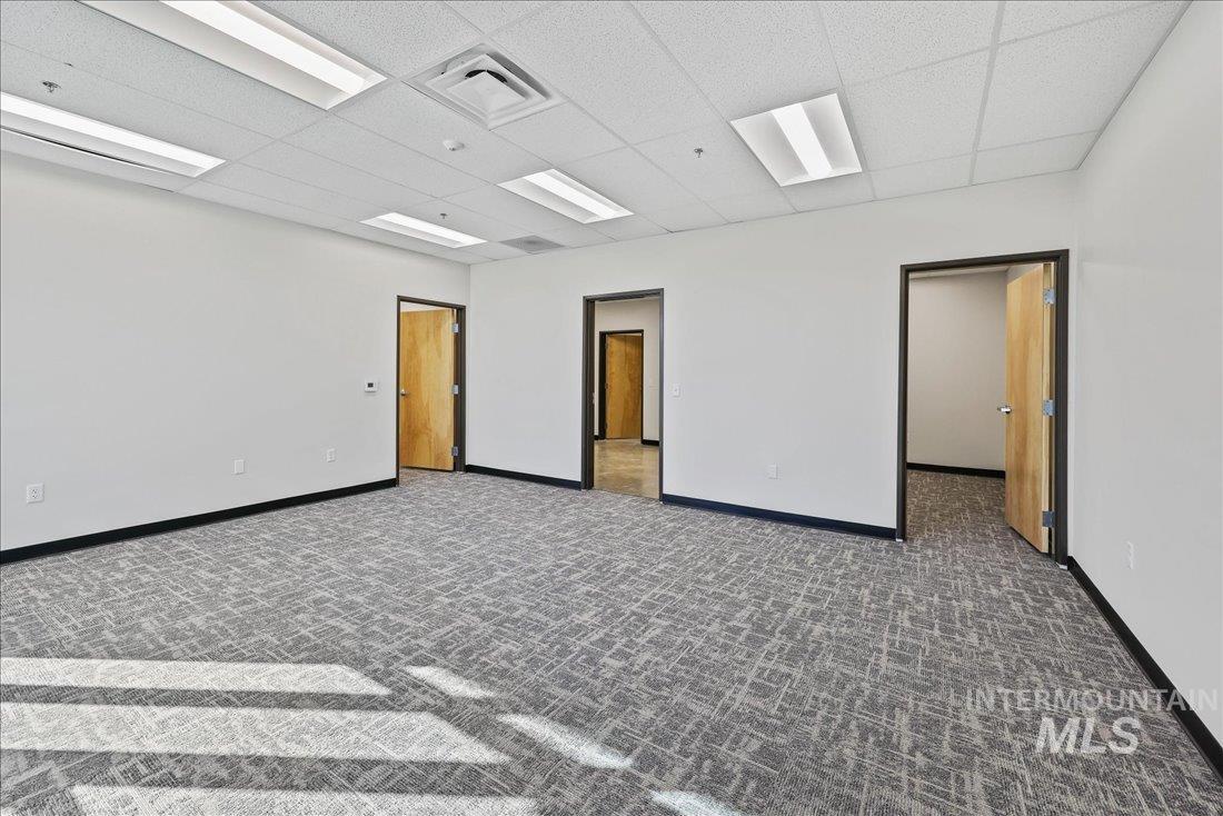 Empty room featuring a paneled ceiling and dark colored carpet