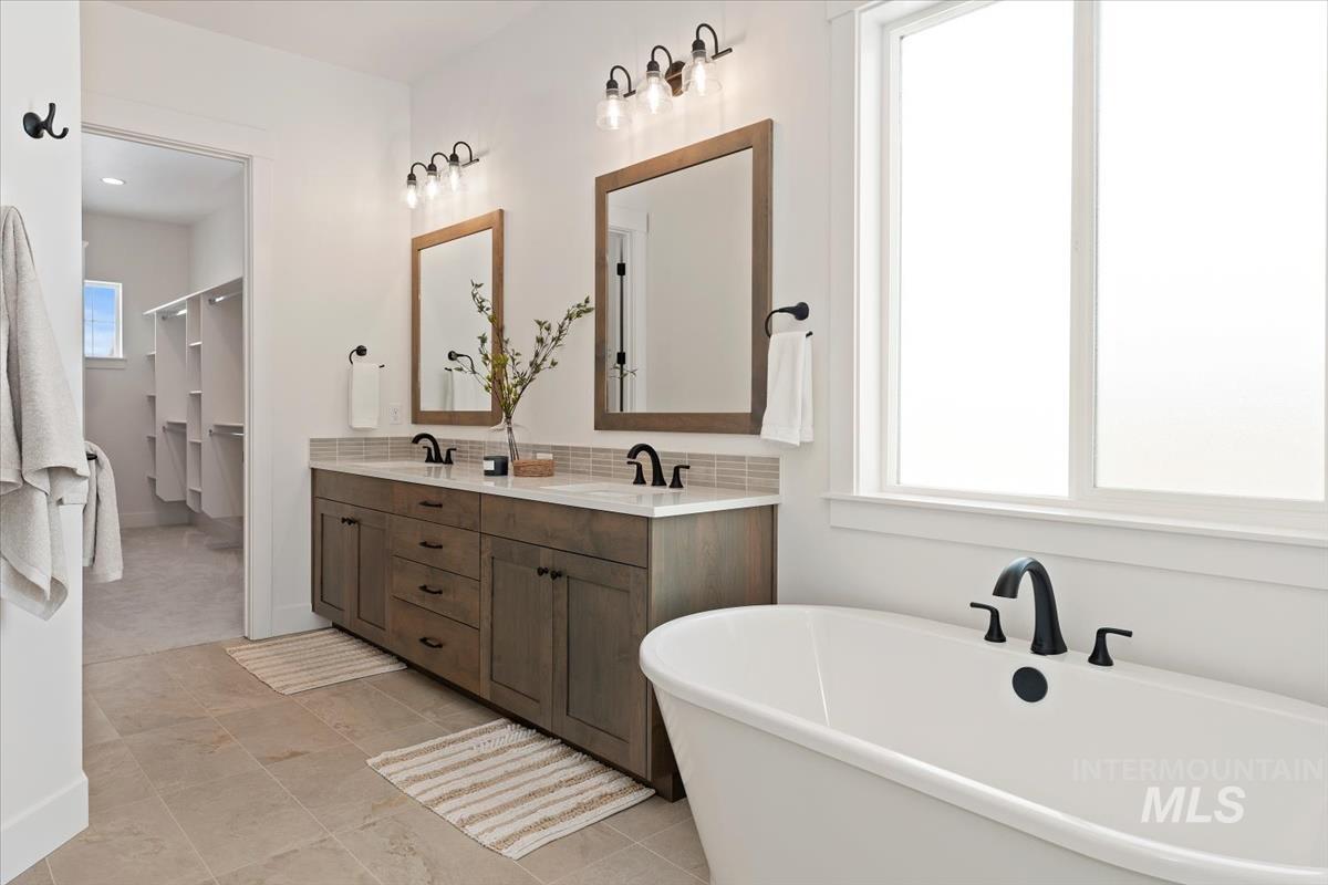 Bathroom featuring a freestanding bath, double vanity, and tasteful backsplash