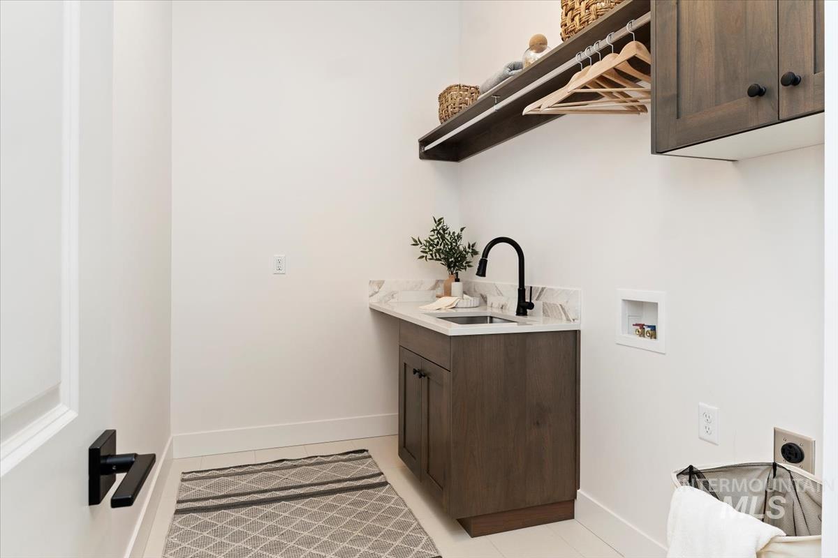 Laundry room with cabinet space, electric dryer hookup, hookup for a washing machine, and light tile patterned floors