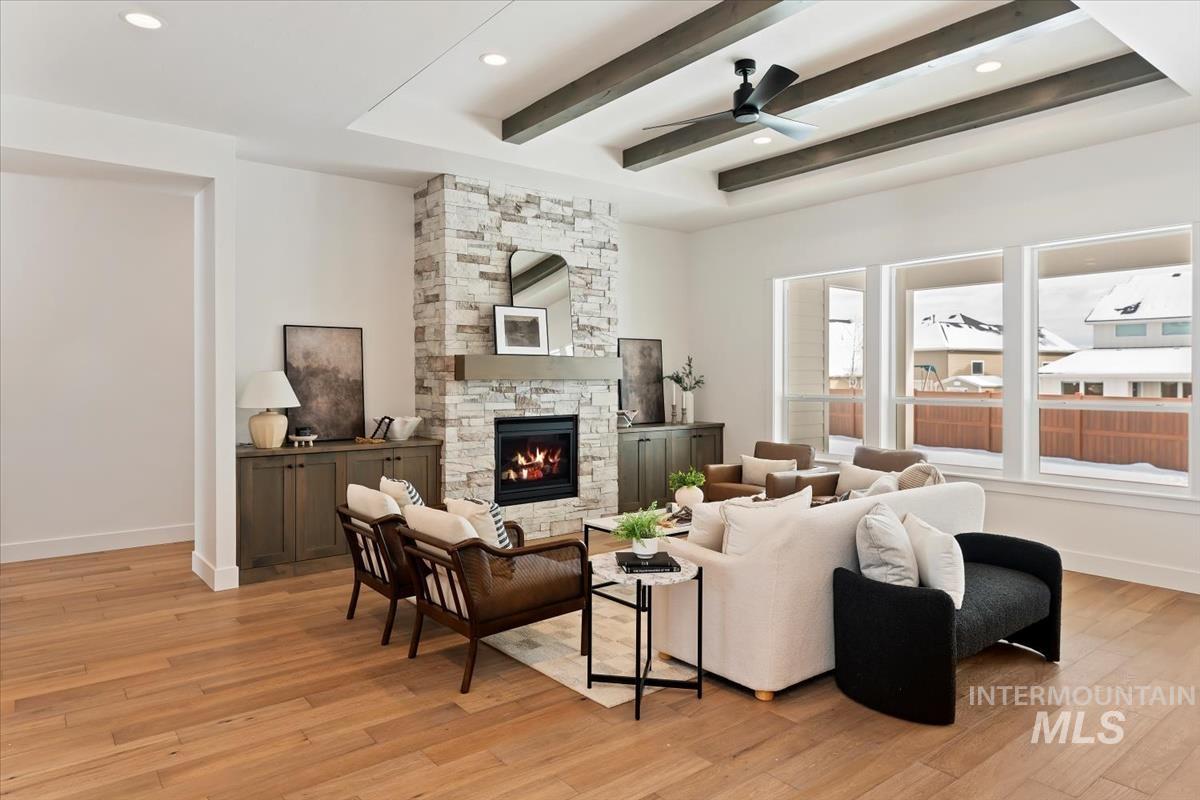 Living room with light wood-style flooring, a stone fireplace, beam ceiling, a ceiling fan, and recessed lighting