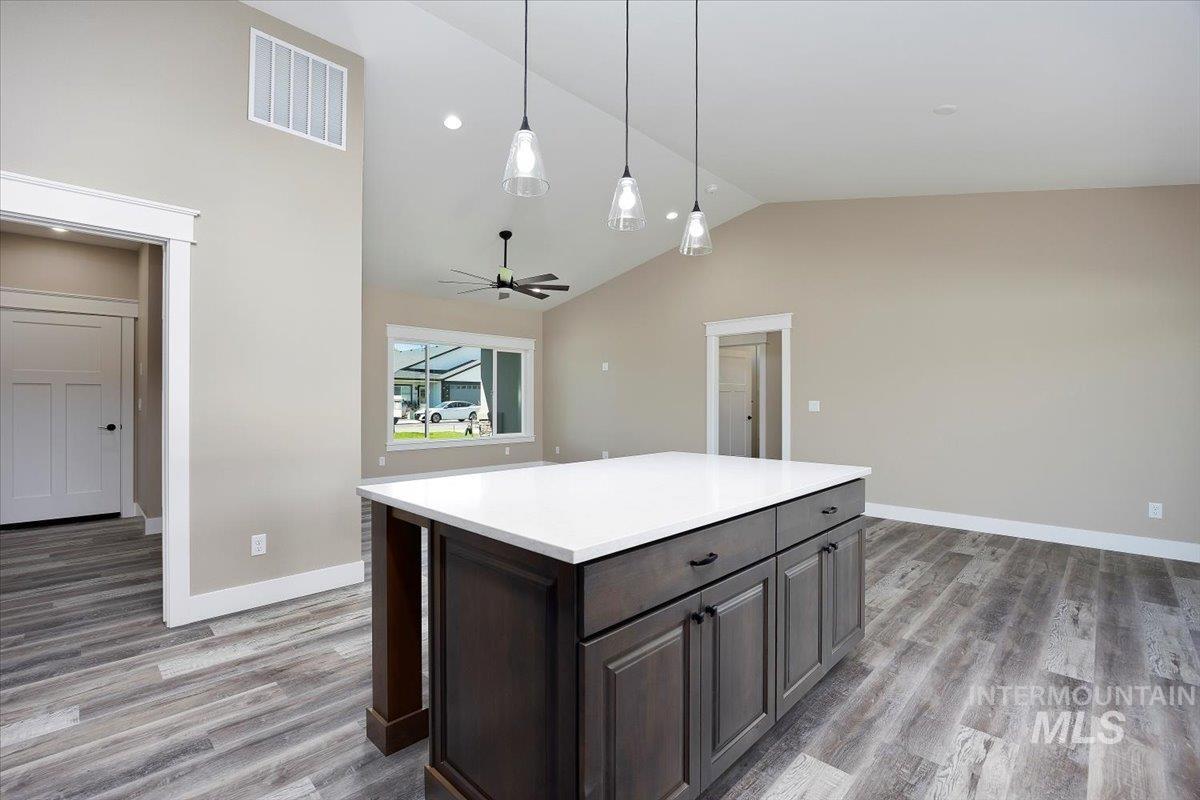Kitchen featuring pendant lighting, a center island, light wood finished floors, ceiling fan, and high vaulted ceiling