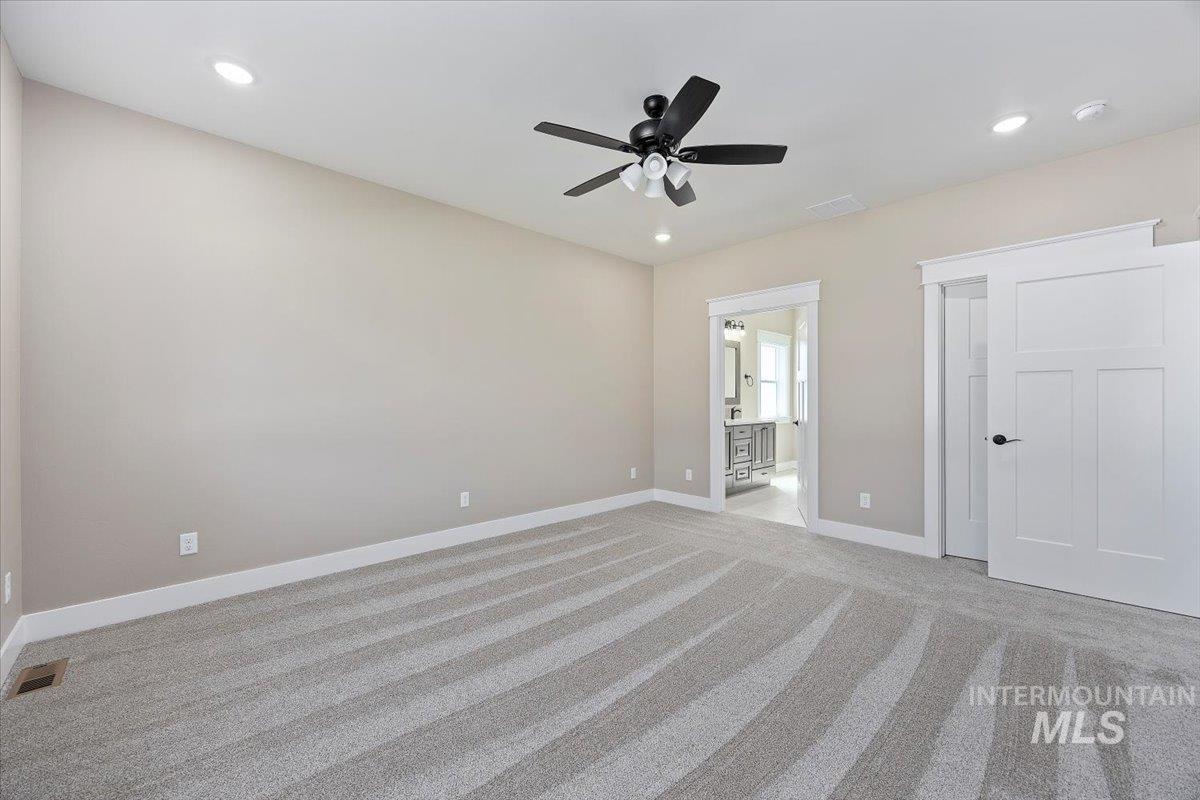 Unfurnished bedroom with light carpet, recessed lighting, ensuite bathroom, and a ceiling fan