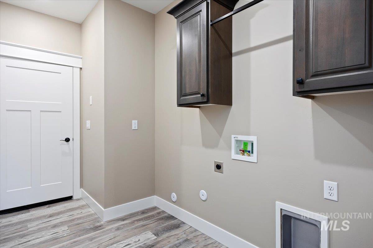 Washroom with cabinet space, hookup for a washing machine, light wood-style floors, and electric dryer hookup