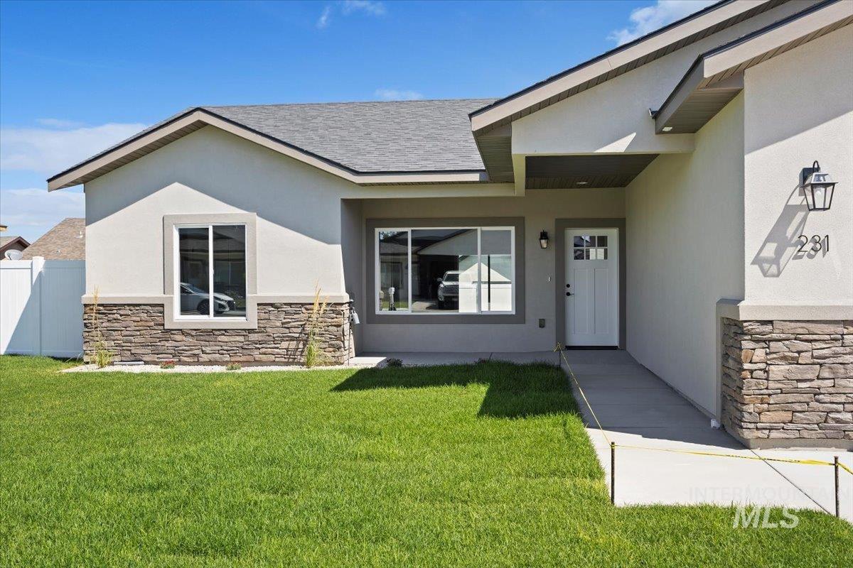 View of exterior entry with stone siding, stucco siding, and a shingled roof
