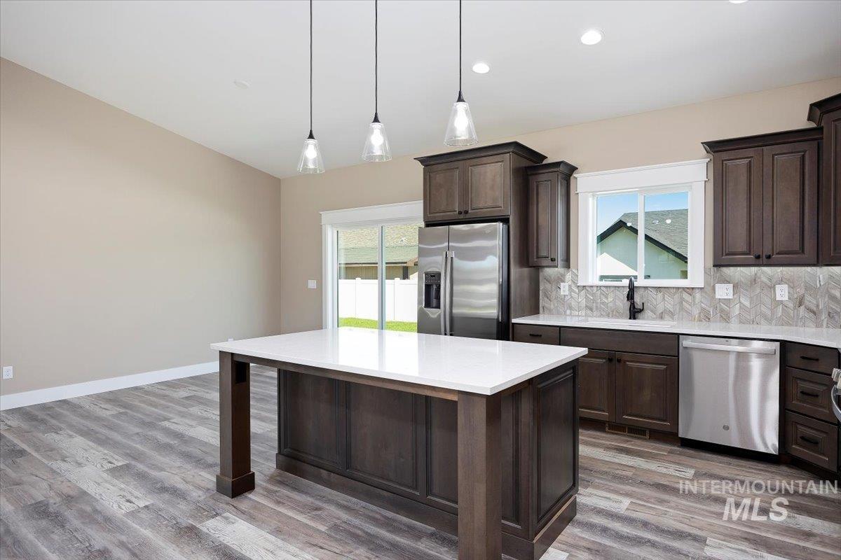 Kitchen featuring dark brown cabinetry, appliances with stainless steel finishes, hanging light fixtures, healthy amount of natural light, and recessed lighting