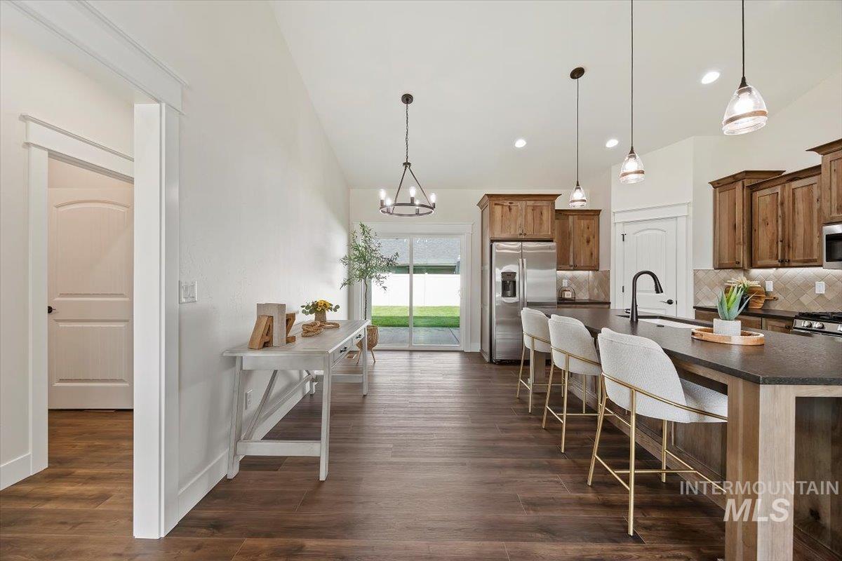Kitchen with decorative backsplash, hanging light fixtures, stainless steel appliances, an island with sink, and recessed lighting
