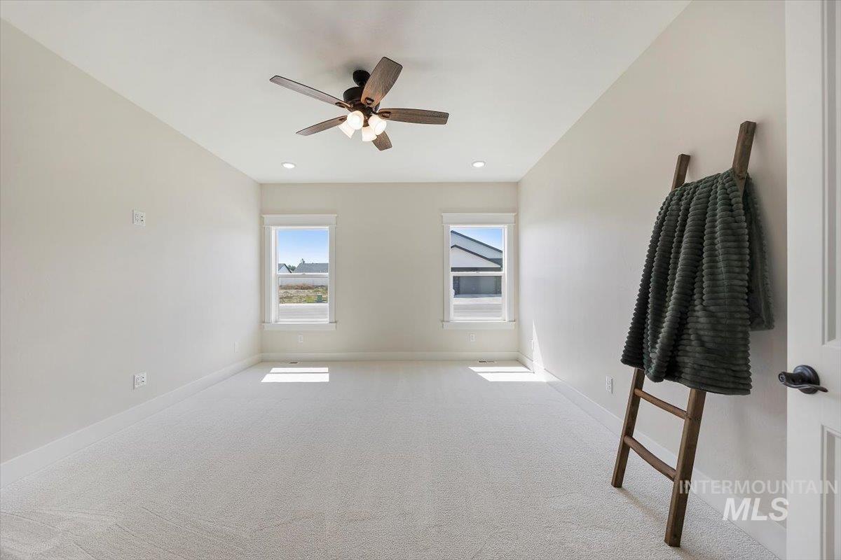 Carpeted empty room with ceiling fan and recessed lighting