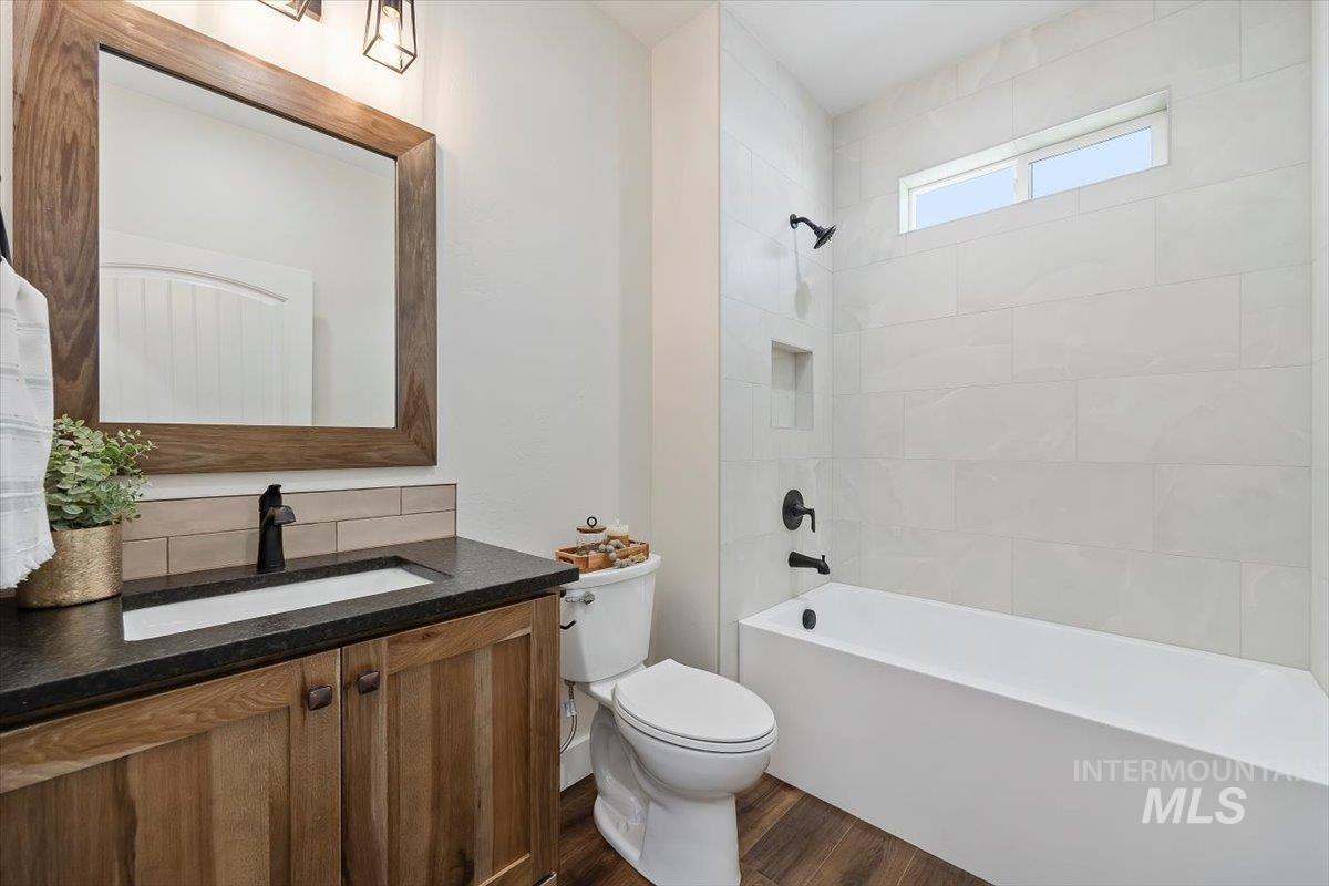 Full bathroom with vanity, tub / shower combination, and dark wood-type flooring