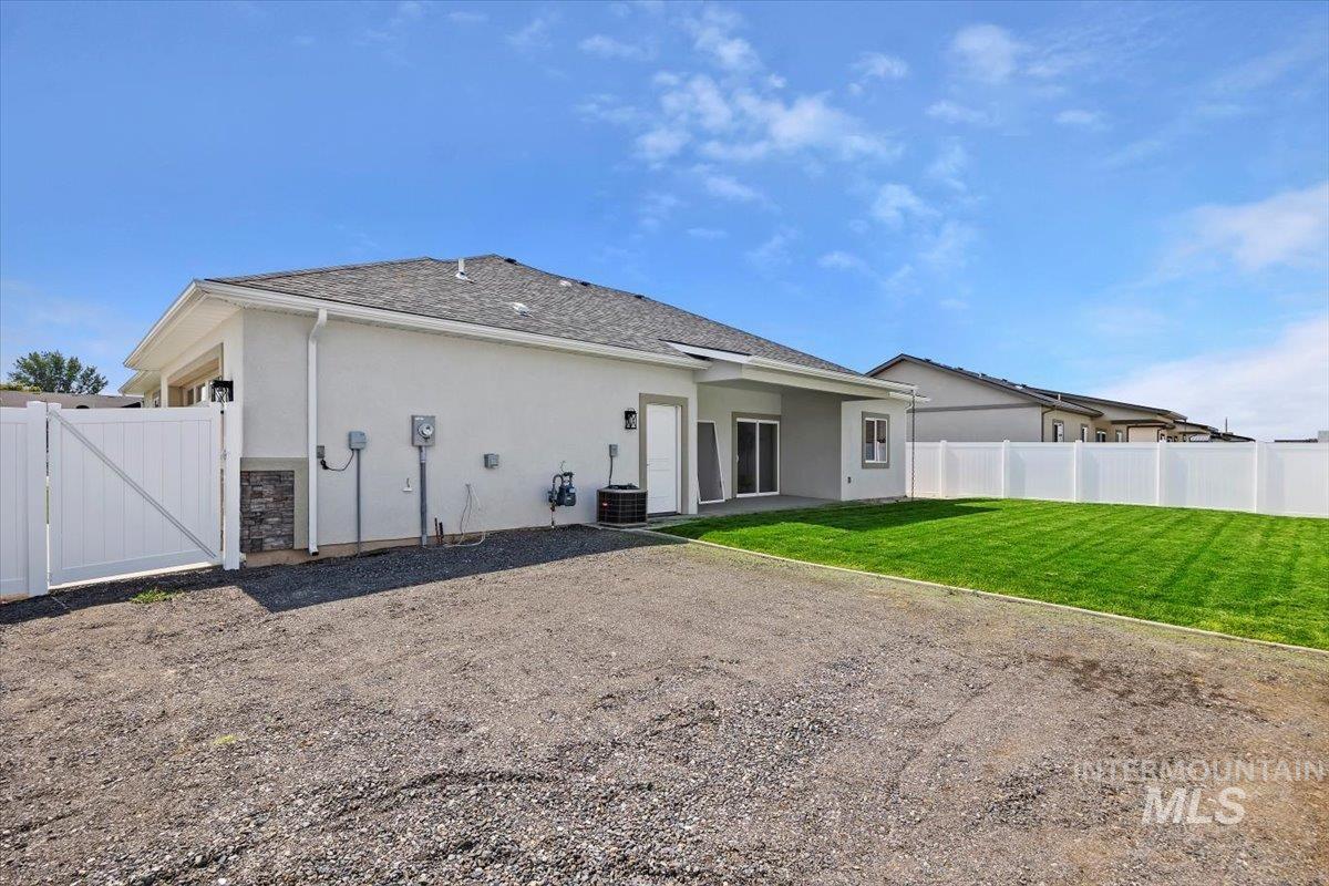 Back of property with a patio area, stucco siding, a gate, and a shingled roof