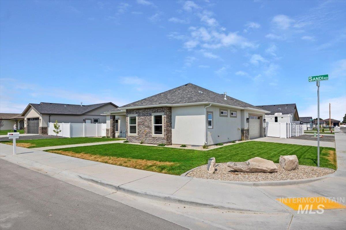 View of front of home featuring a garage, stucco siding, stone siding, and driveway