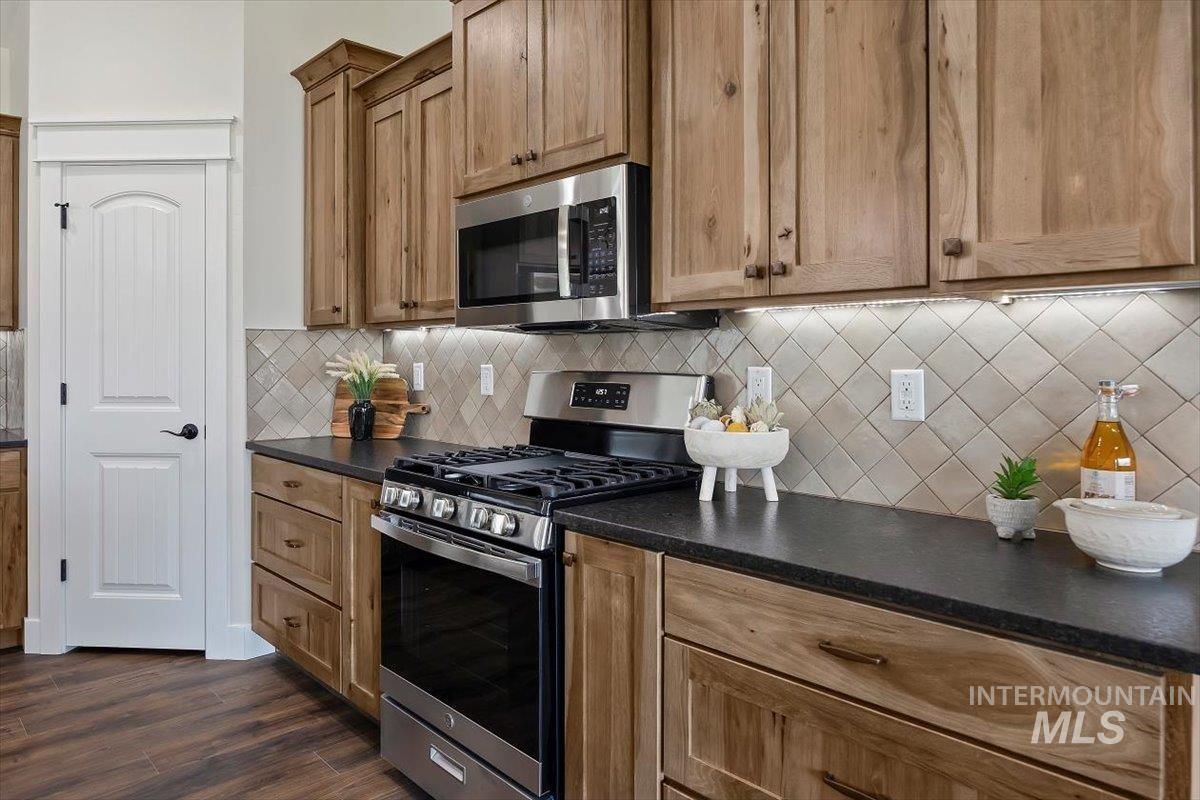 Kitchen with appliances with stainless steel finishes, decorative backsplash, and dark wood-style floors