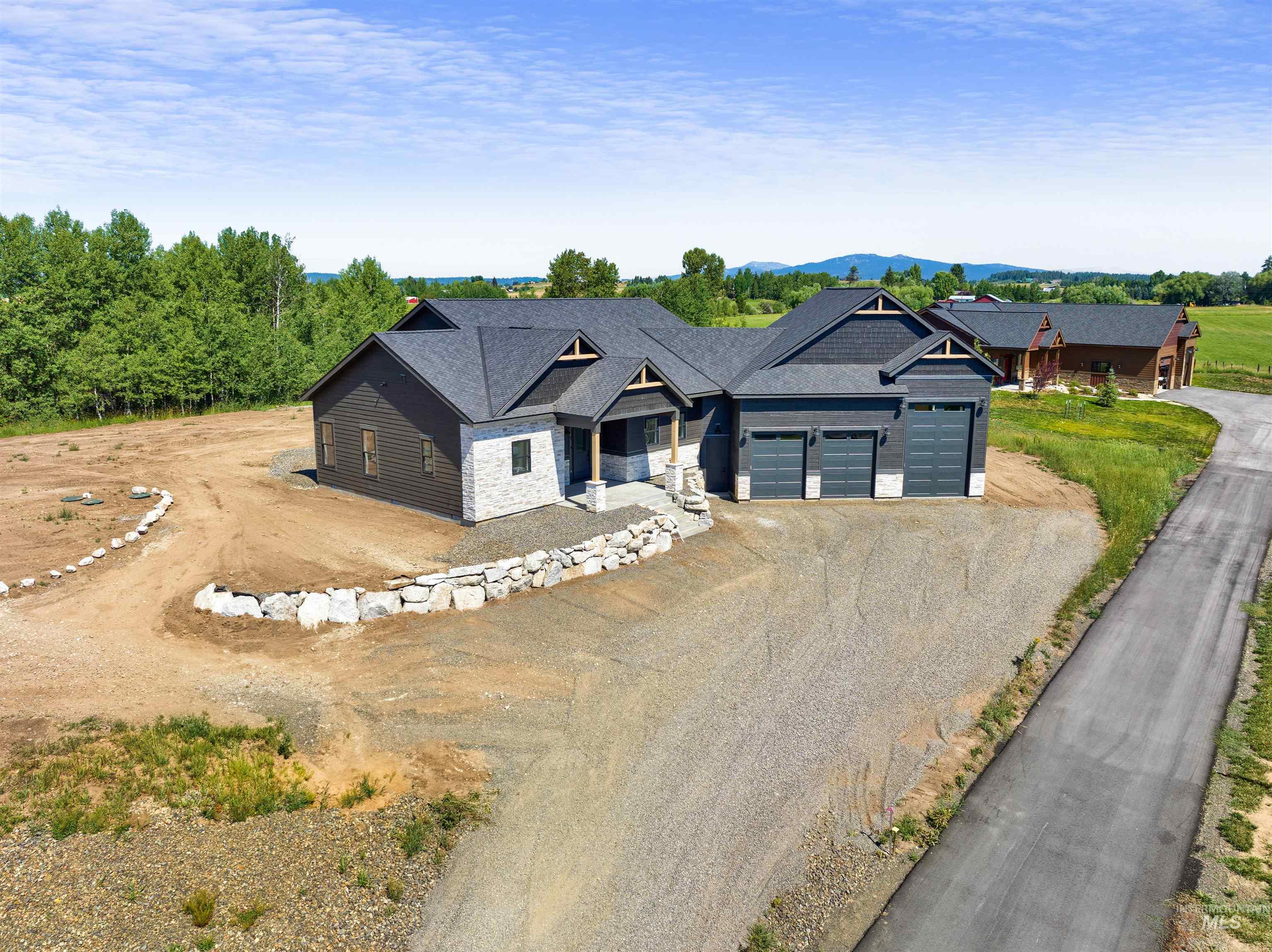 View of front of property with driveway, an attached garage, stone siding, and a mountain view