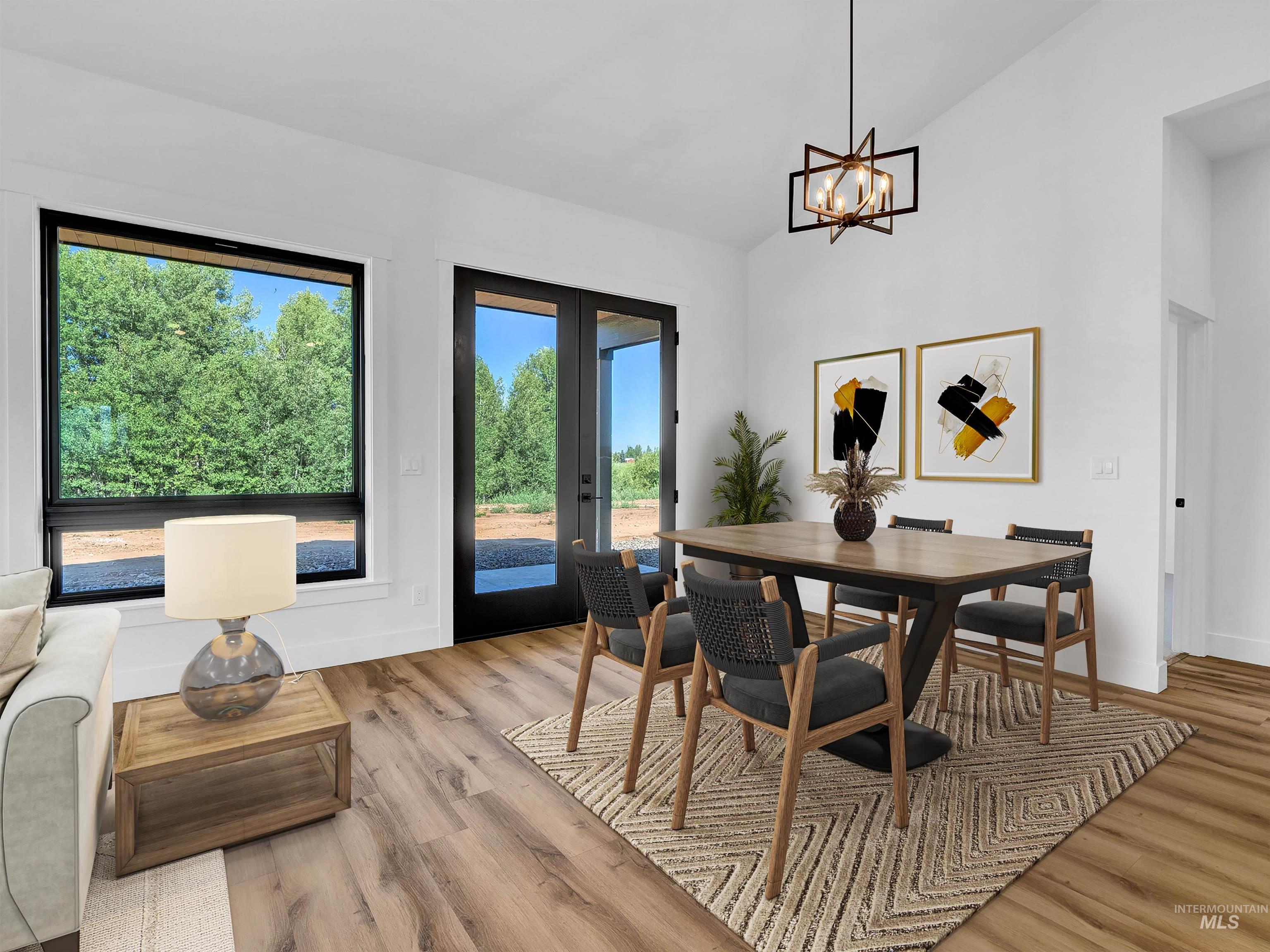 Dining space featuring french doors, light wood-style flooring, a chandelier, and high vaulted ceiling