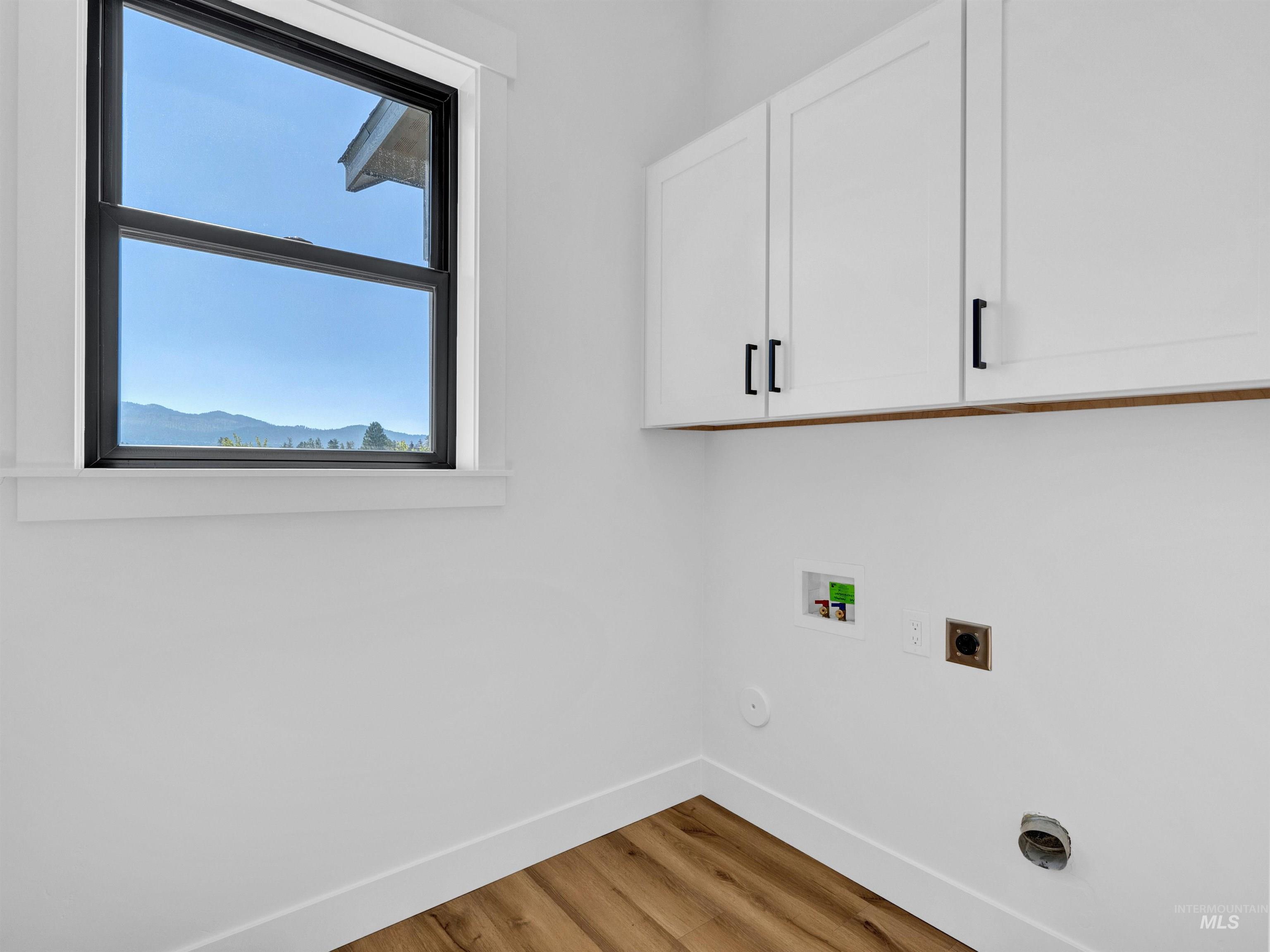 Laundry area featuring electric dryer hookup, cabinet space, wood finished floors, and hookup for a washing machine